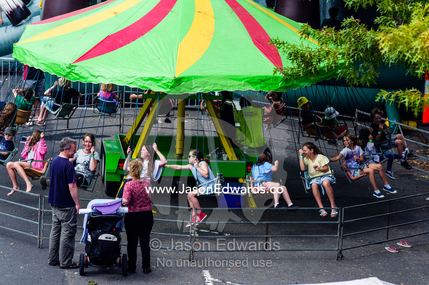Children ride a merry-go-round at a inner cit school fete fundraiser. Carlton North, Melbourne, Victoria, Australia.