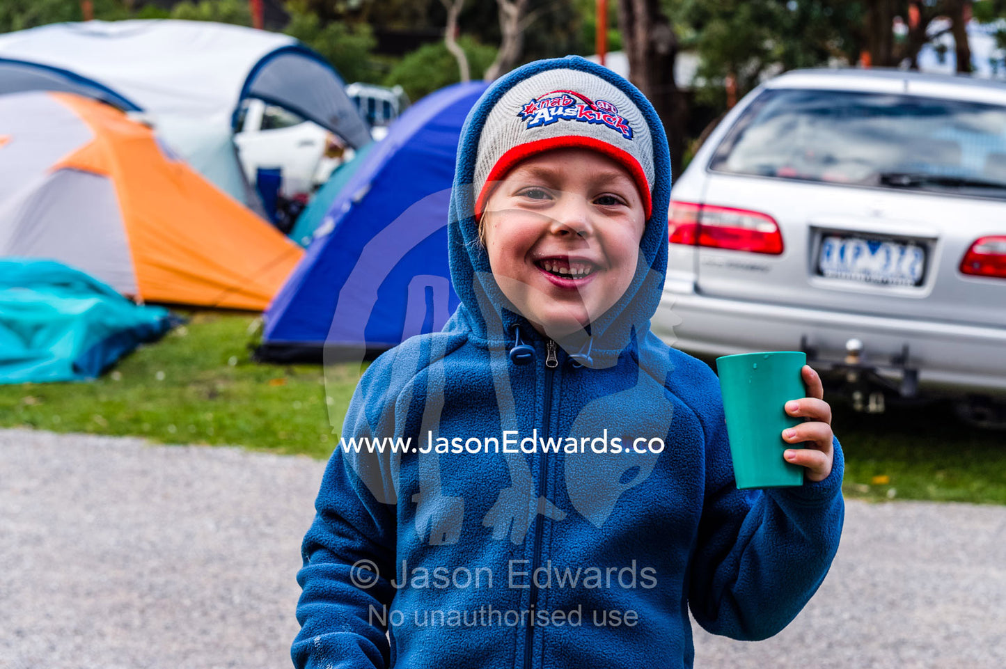 A boy drinks a hot chocolate after cold stormy night camping. Tidal River, Wilsons Promontory National Park, Victoria, Australia.