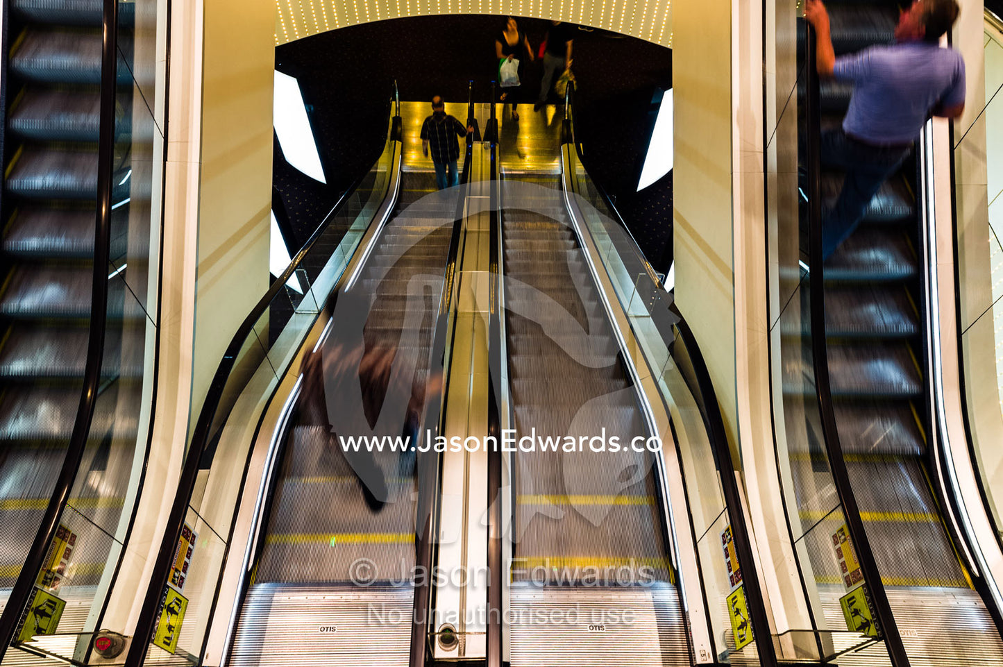 A stainless steel escalator descends between levels in a casino. Crown Casino, Southbank, Melbourne, Victoria, Australia.
