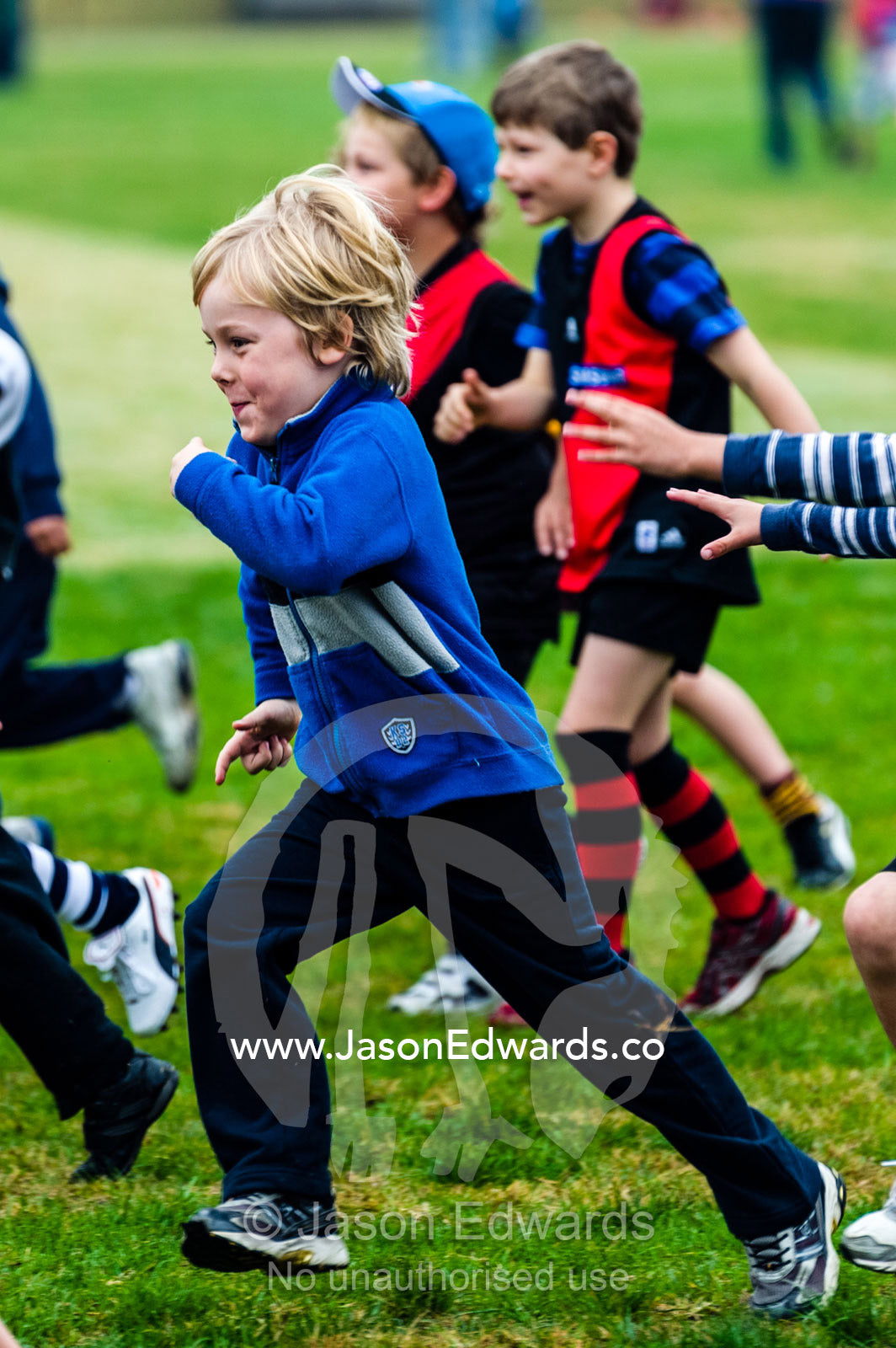 An excited boy running laps at a football training camp. Edinburgh Gardens, Fitzroy North, Melbourne, Victoria, Australia.