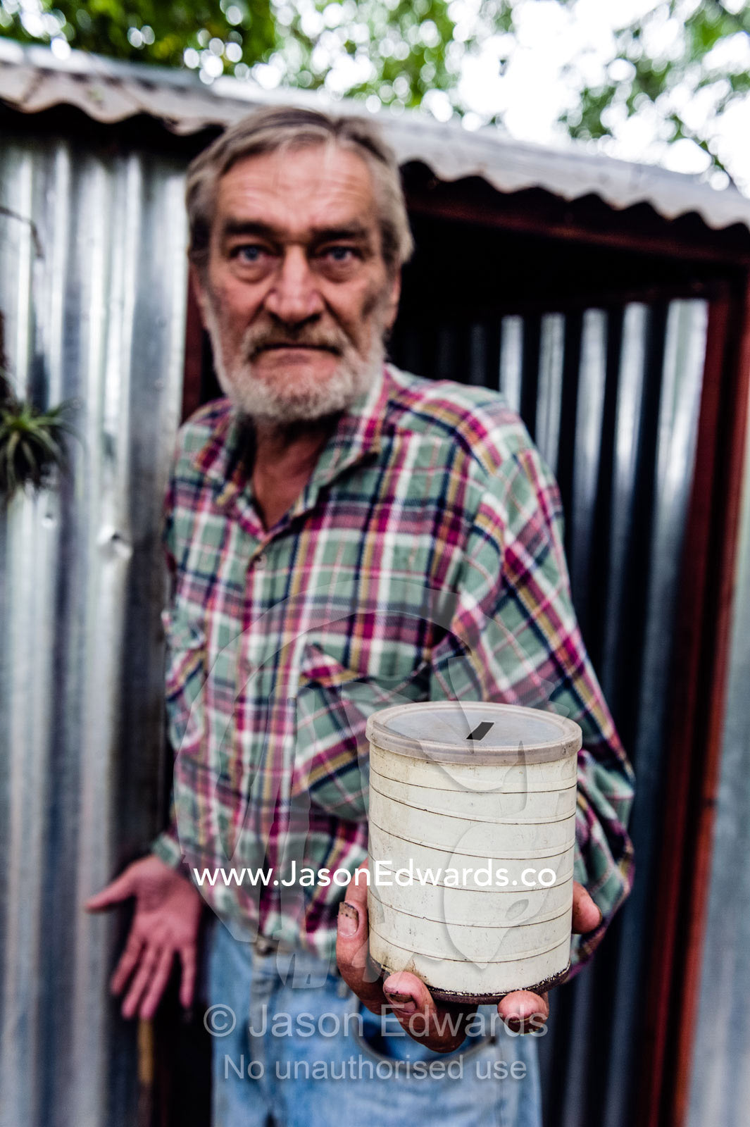 A man with his begging can in a community of displaced people.. Bon Accord Dam, Gauteng Province, South Africa.