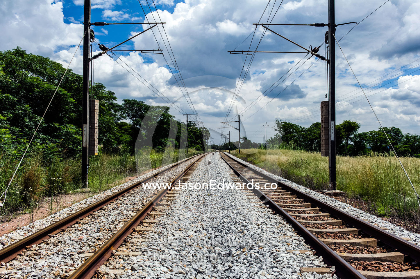 Dual railway tracks march across the flat veld towards Pretoria. Rooiwal, Rooiwal Power Station, Gauteng Province, South Africa.