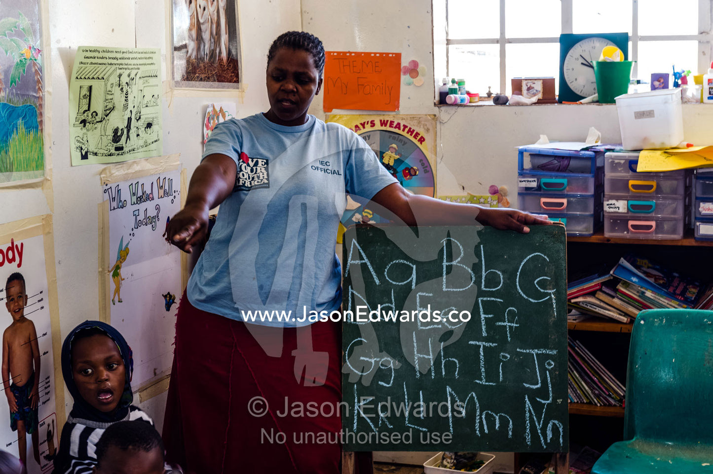 A teacher helps a student with the letters of the alphabet at school. Red Hill Township and Pre-School, Cape Town, Western Cape, South Africa.