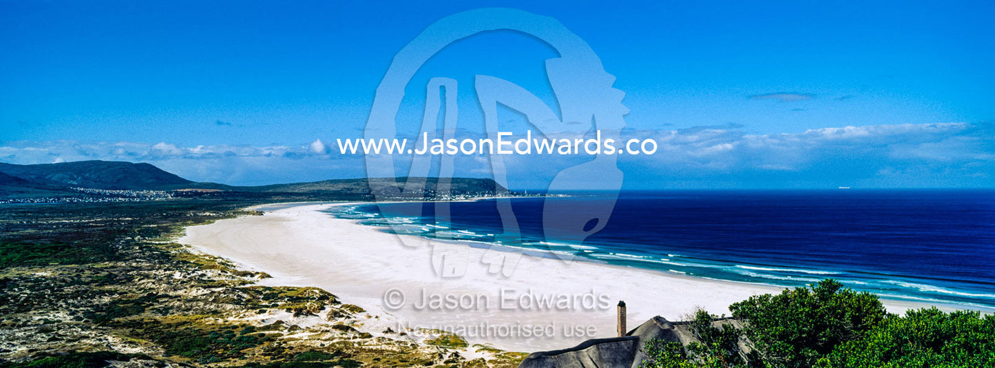 A pristine white sandy beach along a wide bay under a summer sky. Noordhoek Beach, Cape Town, Chapmans Peak Drive, Western Cape, South Africa.