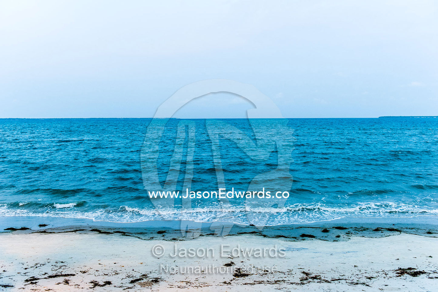 Tropical waves from the ocean lap the sandy shoreline of a bay after sunset. Dar es Salaam, Kawe, Tanzania.