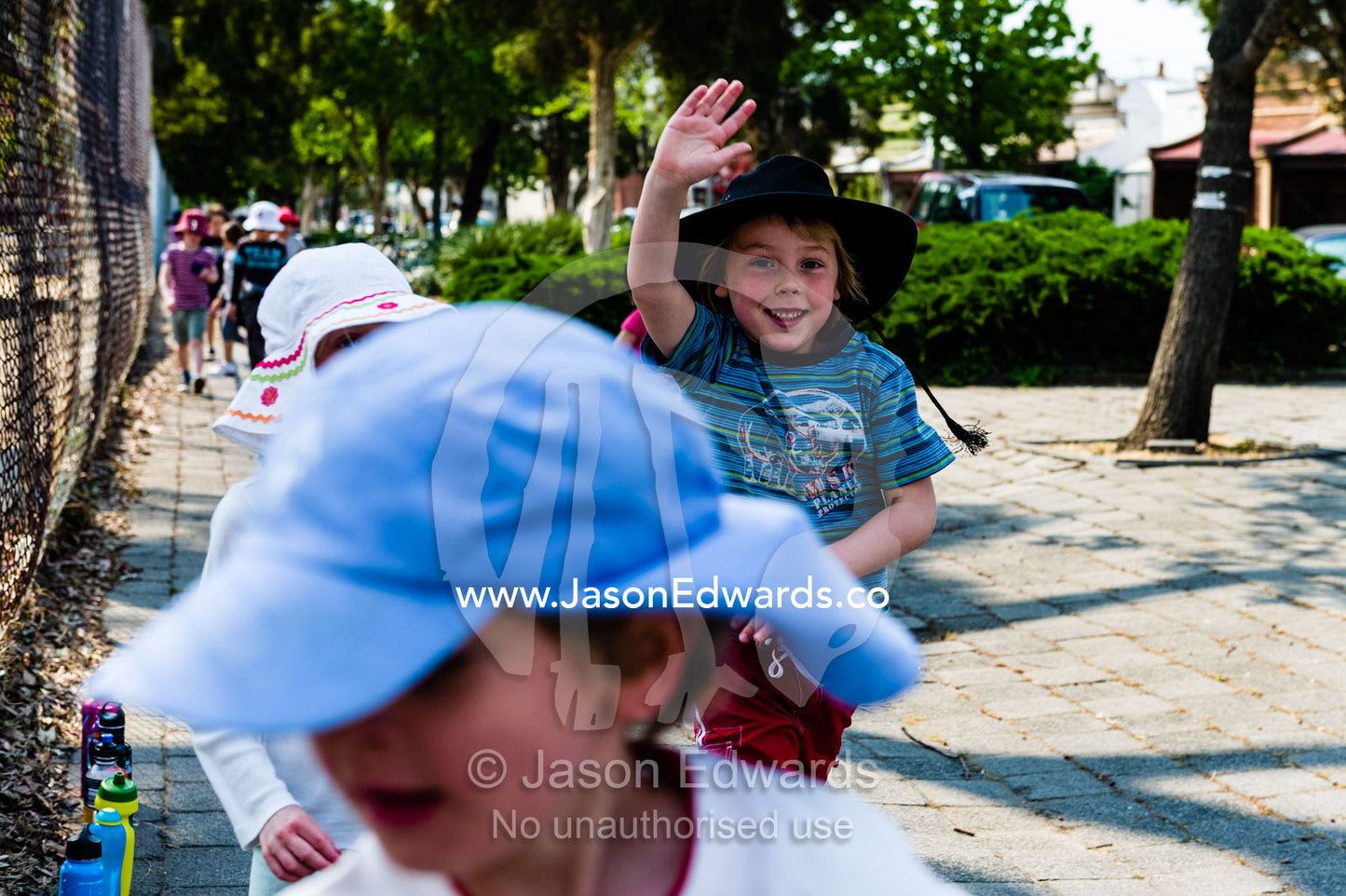A boy waves as he raises funds for his school on a summer walkathon. Carlton North Primary School, Carlton North, Melbourne, Victoria, Australia.