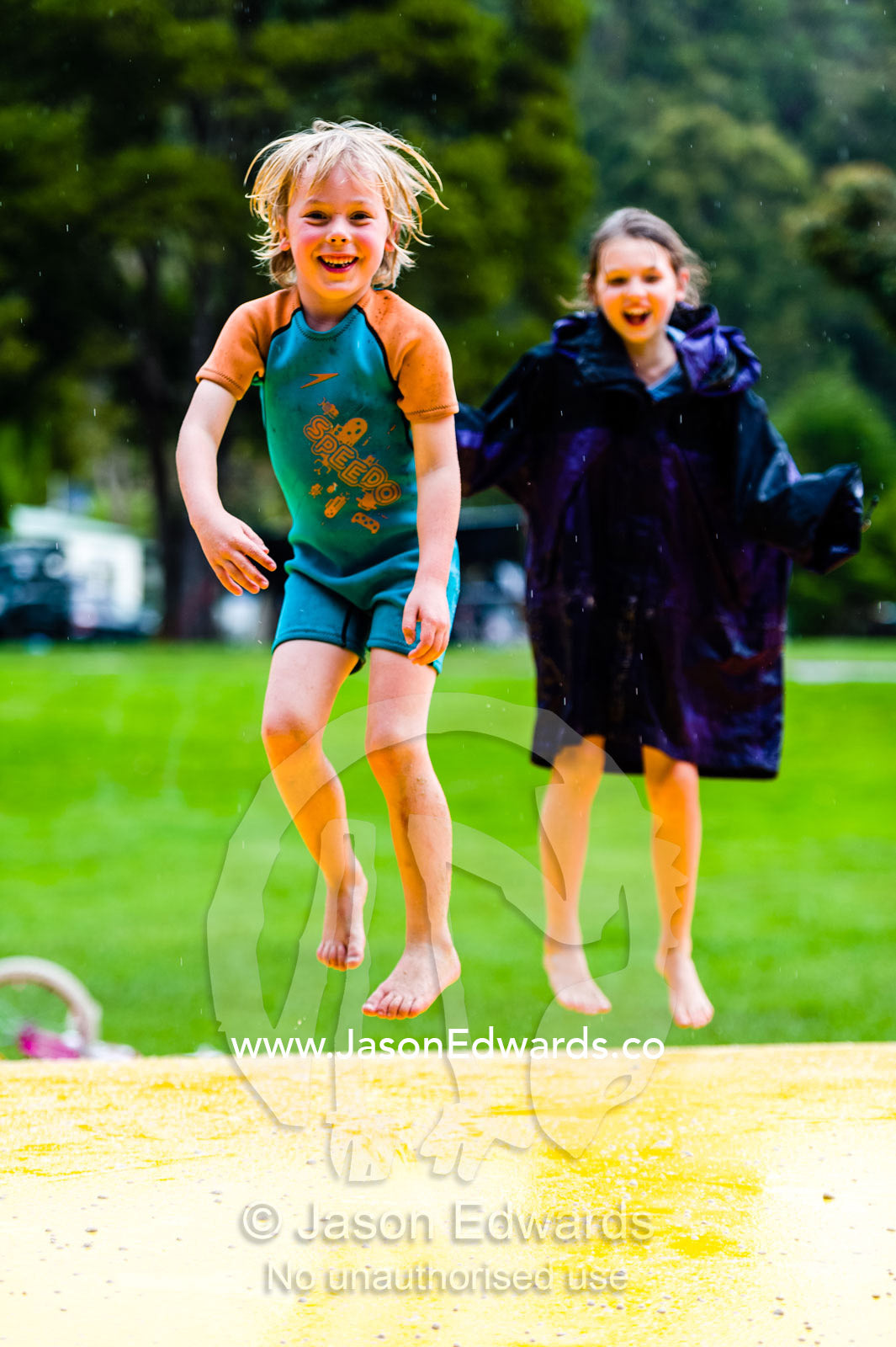Children laughing and having fun jumping on an inflatable cushion. Wye River, Great Ocean Road, Victoria, Australia.