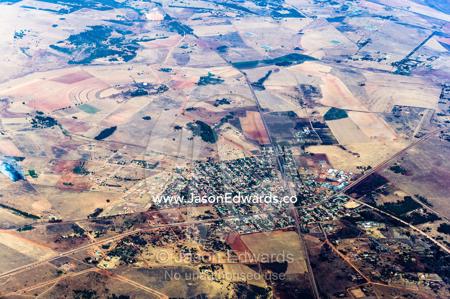 The urban sprawl of a village surrounded by a vast plain dotted with agricultural land and farms. Johannesburg, Gauteng Province, South Africa, Africa.