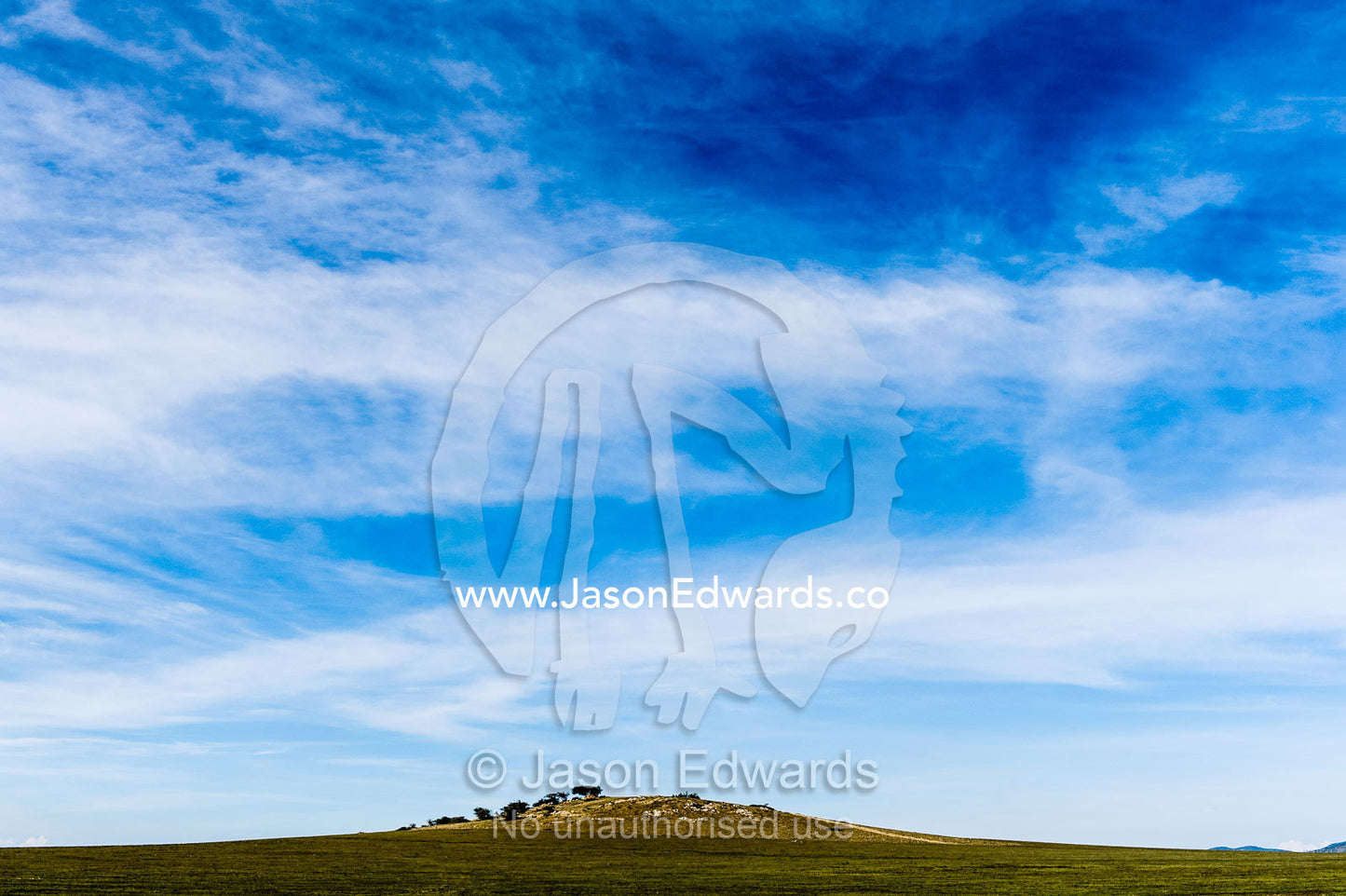 A island granite outcrop known as a kopje on the vast, flat savannah plain. Ngorongoro Conservation Area, Ngorongoro District, Tanzania.