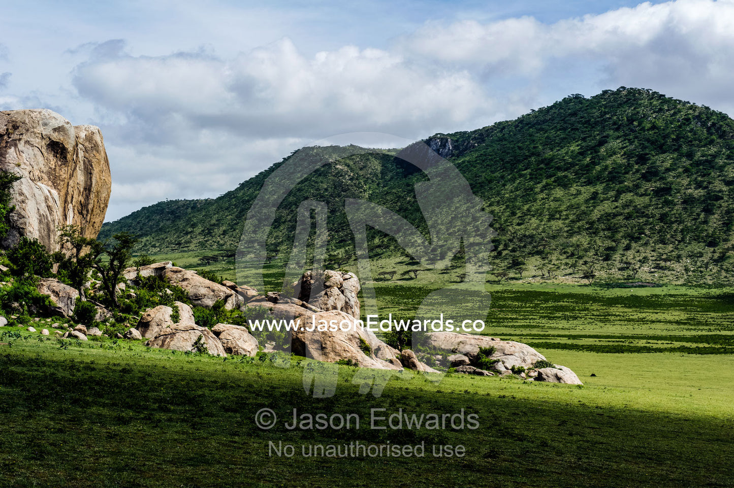 A tumble of granite boulders known as a kopje rises over the savannah plain. Ngorongoro Conservation Area, Ngorongoro District, Tanzania.