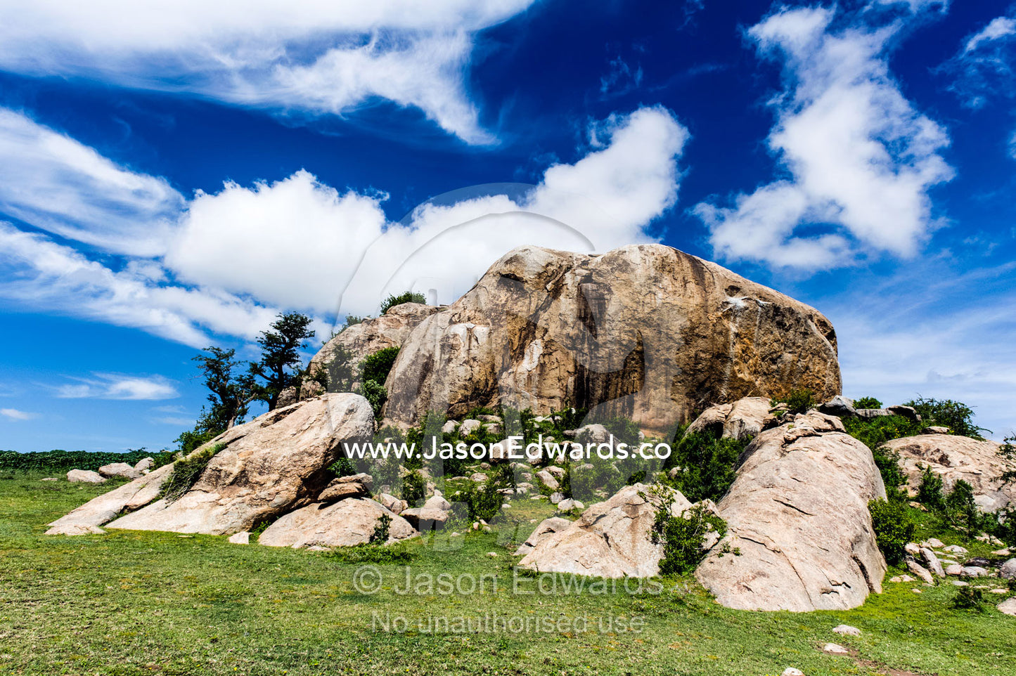 Wispy clouds crowning a rocky granite outcrop on the savannah known as a kopje. Ngorongoro Conservation Area, Ngorongoro District, Tanzania.