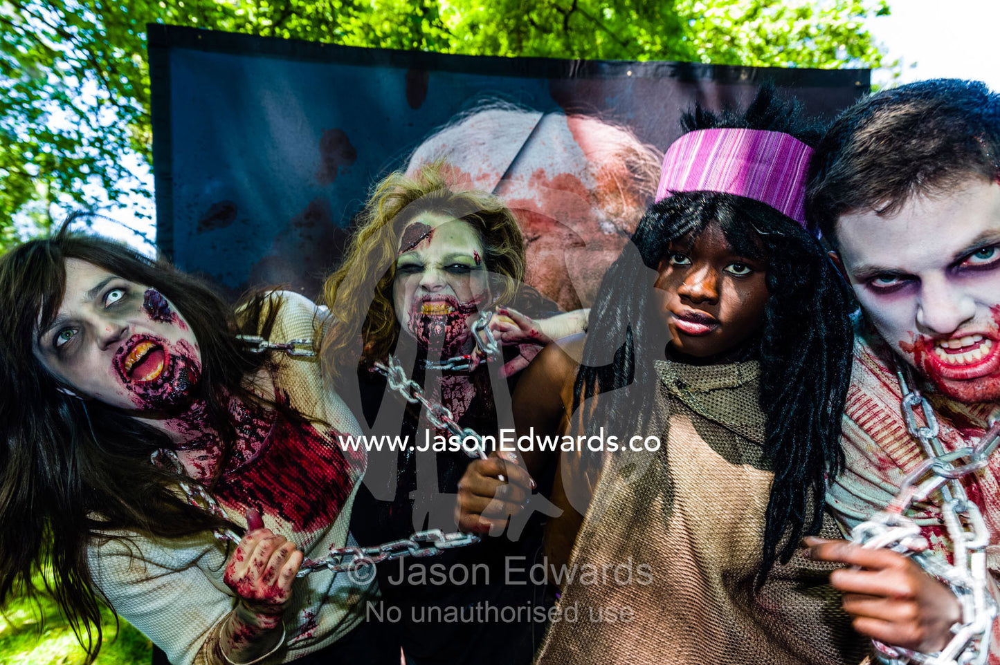 People dressed as zombies held by chains by a character from the Walking Dead. Carlton Gardens, World Heritage Site, Carlton, Melbourne, Victoria, Australia.