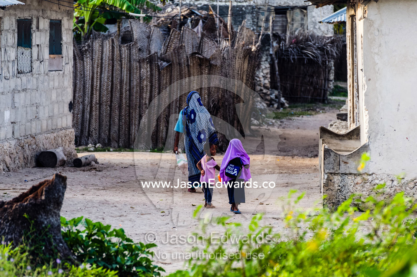 A Muslim mother and her daughters walking through lanes in an island village. Unguja Island, Zanzibar, Tanzania, Africa.