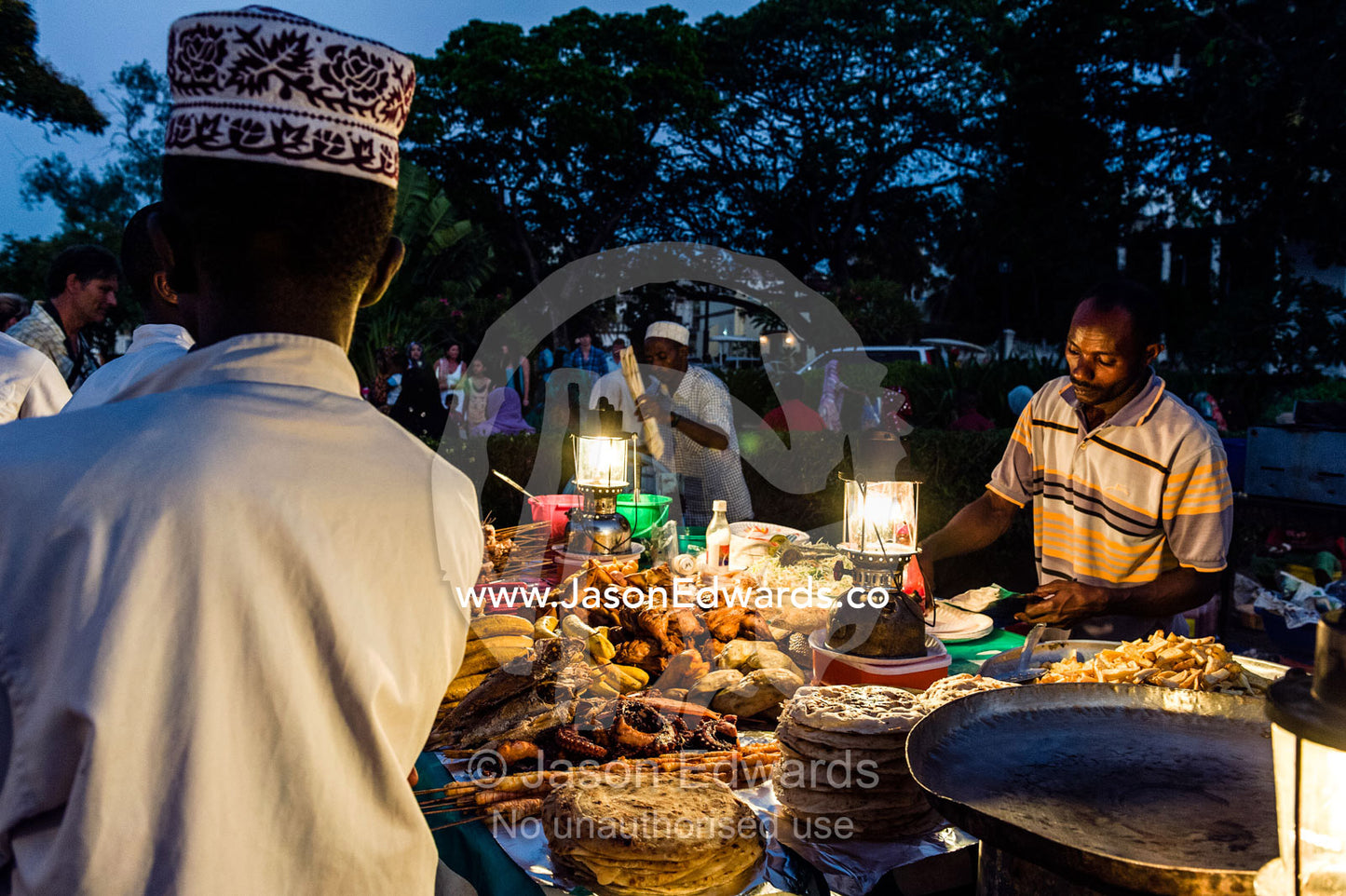 Food stall vendors prepare fresh food for shoppers at a night market by the Indian Ocean. Forodhani Gardens, Stone Town, Mji Mkongwe, Zanzibar, Unguja Island, Zanzibar, Tanzania.
