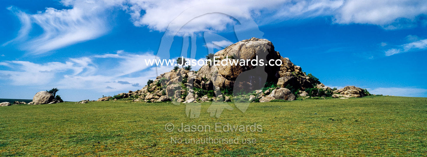A rocky granite outcrop known as a kopje on a short grass savannah plain. Ngorongoro Conservation Area, Ngorongoro District, Tanzania.