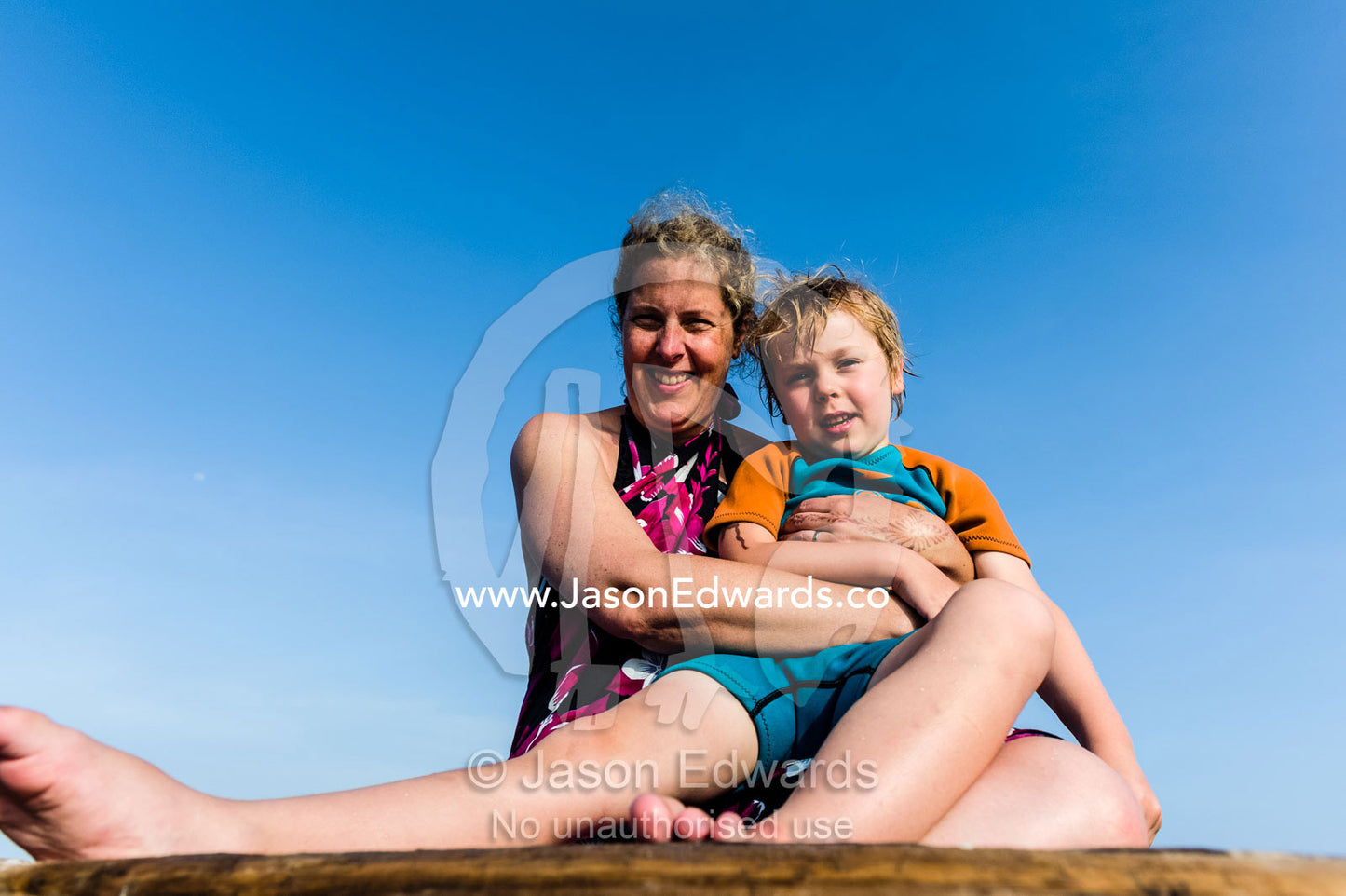 A mother and son cuddling whilst sailing happily on a wooden dhow fishing boat. Bwejuu, Blue Lagoon Reef, Unguja Island, Zanzibar, Tanzania.