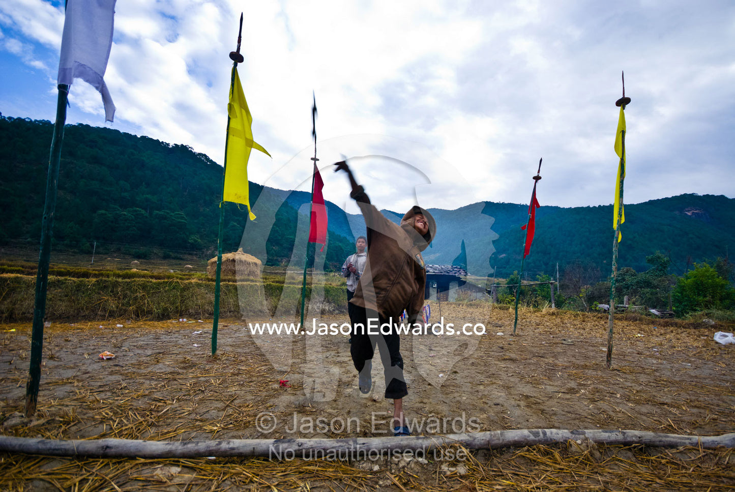 A village boy throws a large wooden dart known as khuru that is played during festivals. Punakha River, Punakha Valley, Punakha-Wangdiphodrang District, Bhutan.