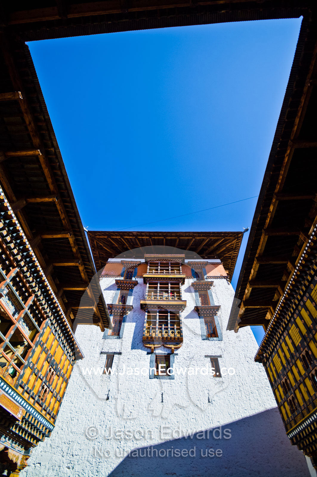 Ornately carved windows and colorful balconies overlook a courtyard in an ancient Buddhist monastery. Rinpung Dzong, Paro Dzong, Paro, Paro District, Bhutan.