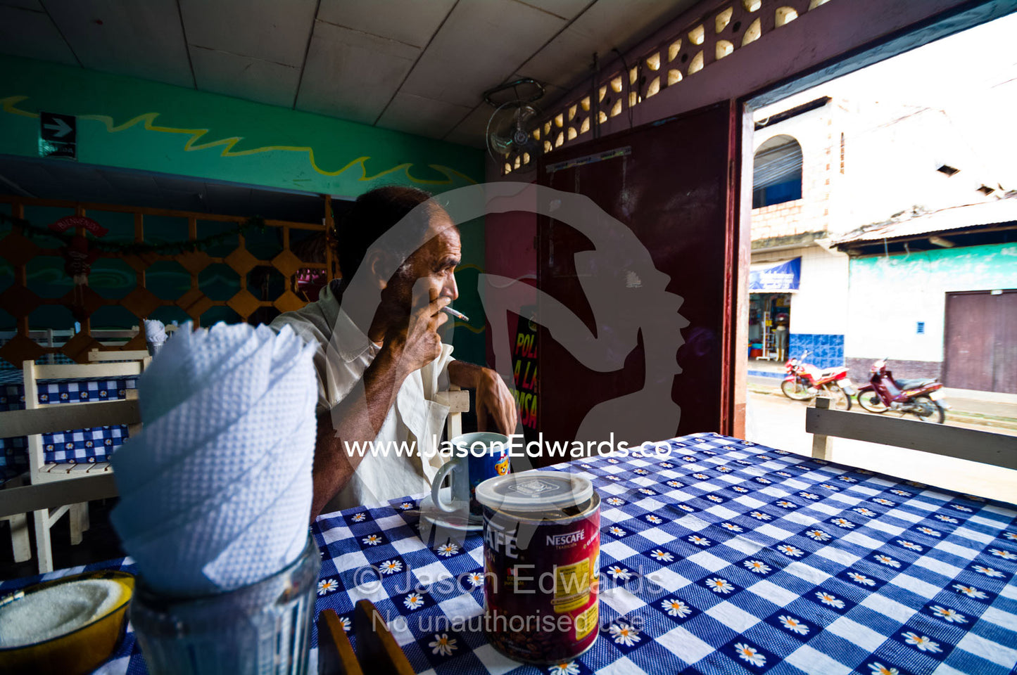 A retired poacher sits with a mug of coffee, dragging on cigarette in a Peruvian restaurant. Nauta, Amazon Basin, Loreto Region, Maynas Province, Peru.