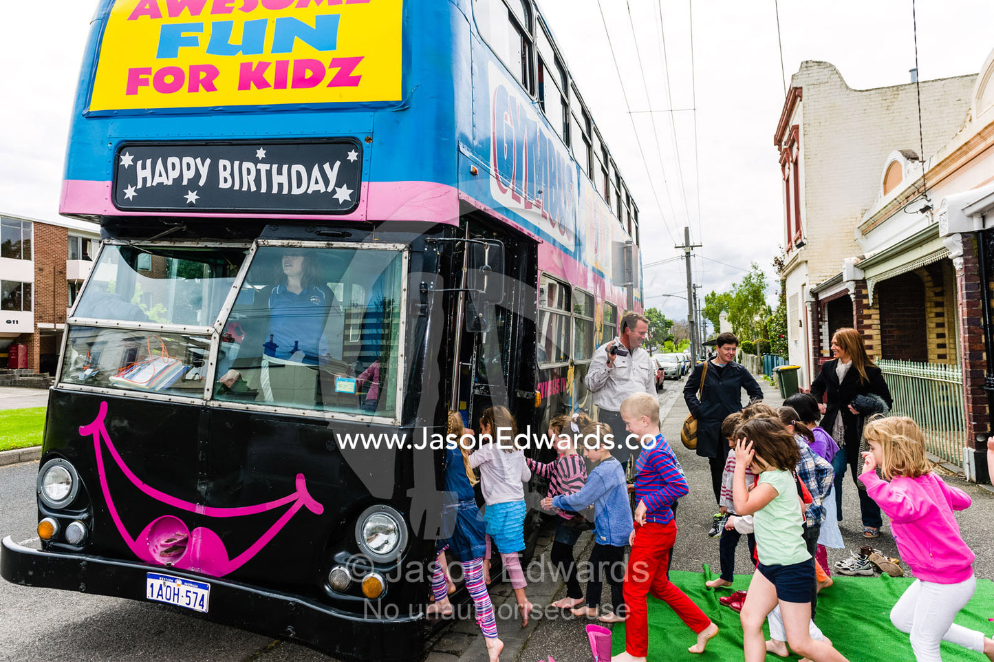 Children rush onto a double-decker bus converted into a birthday party venue for gymnastic activities. Carlton North, Melbourne, Victoria, Australia.