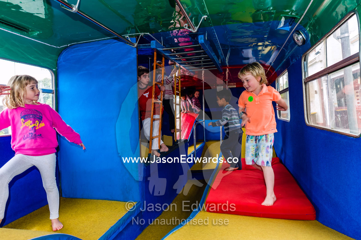 Children playing on a double-decker bus converted into a birthday party venue for gymnastic activities. Carlton North, Melbourne, Victoria, Australia.