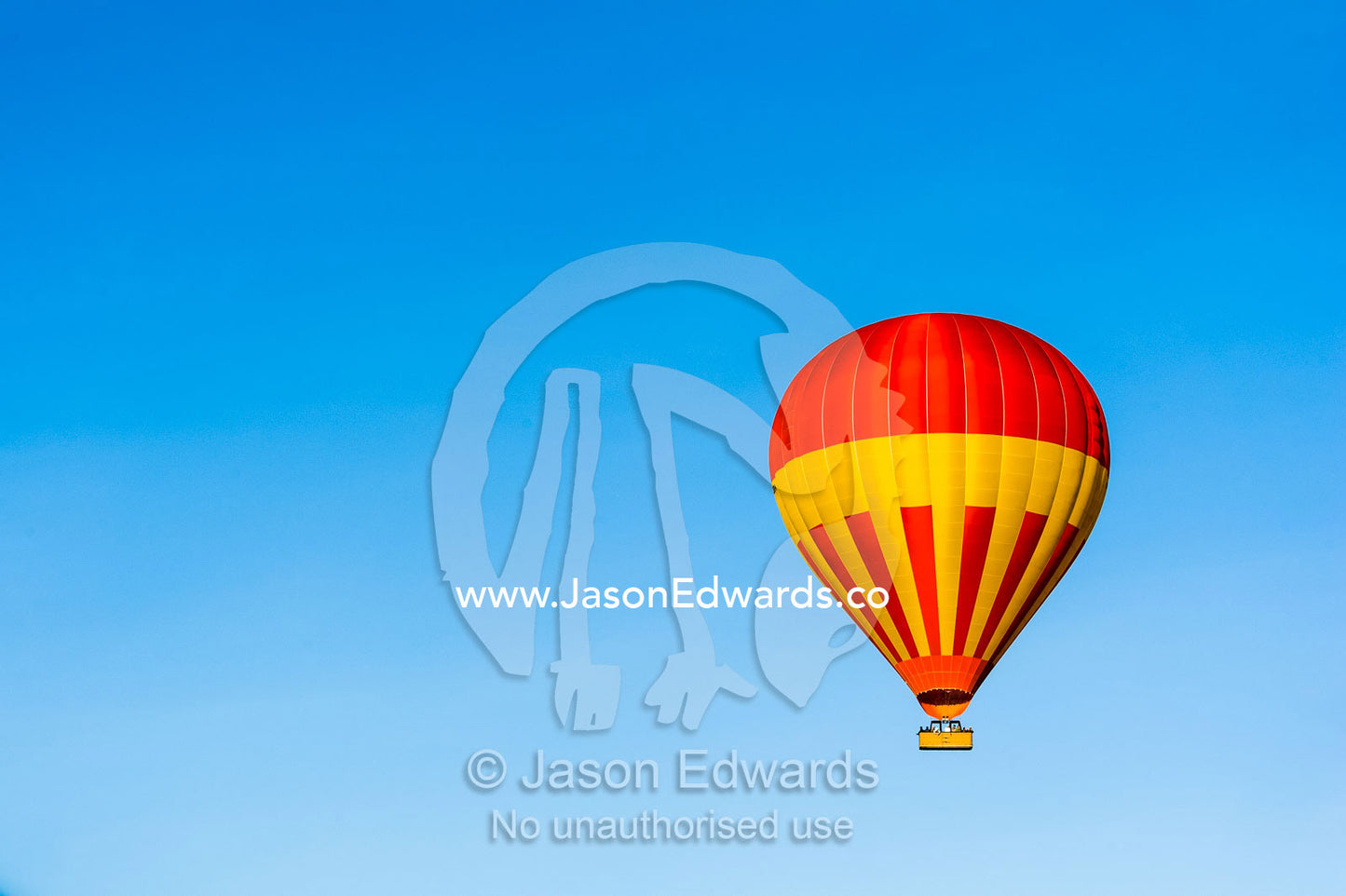A hot air ballon floating in a clear blue sky above the African savannah. Maasai Mara National Reserve, Masai Mara, Narok County, Kenya.