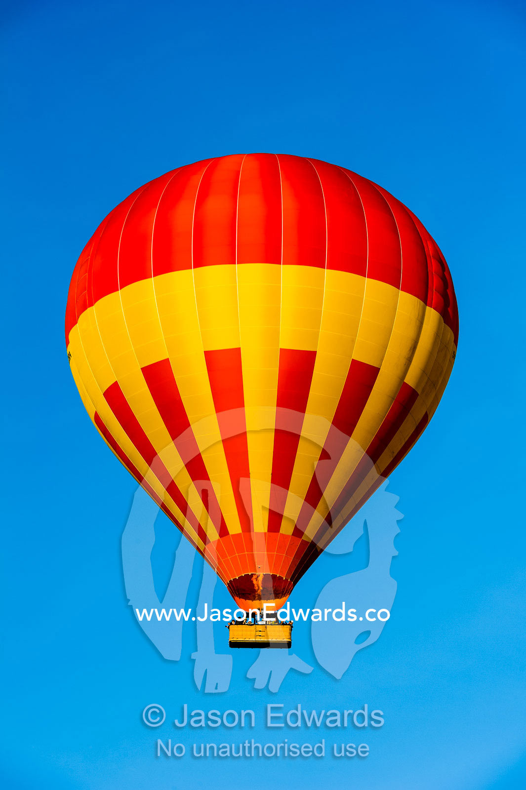 A hot air ballon floating in a clear blue sky above the African savannah. Maasai Mara National Reserve, Masai Mara, Narok County, Kenya.