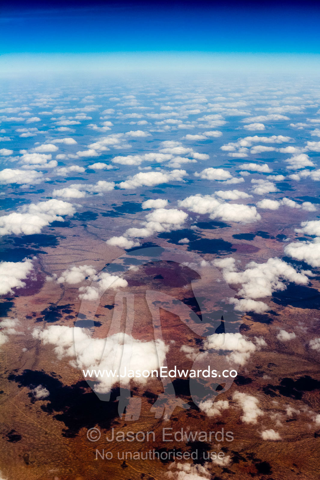 A flotilla of white fluffy clouds casting shadows onto a vast desert plain. Over South-eastern Ethiopia.