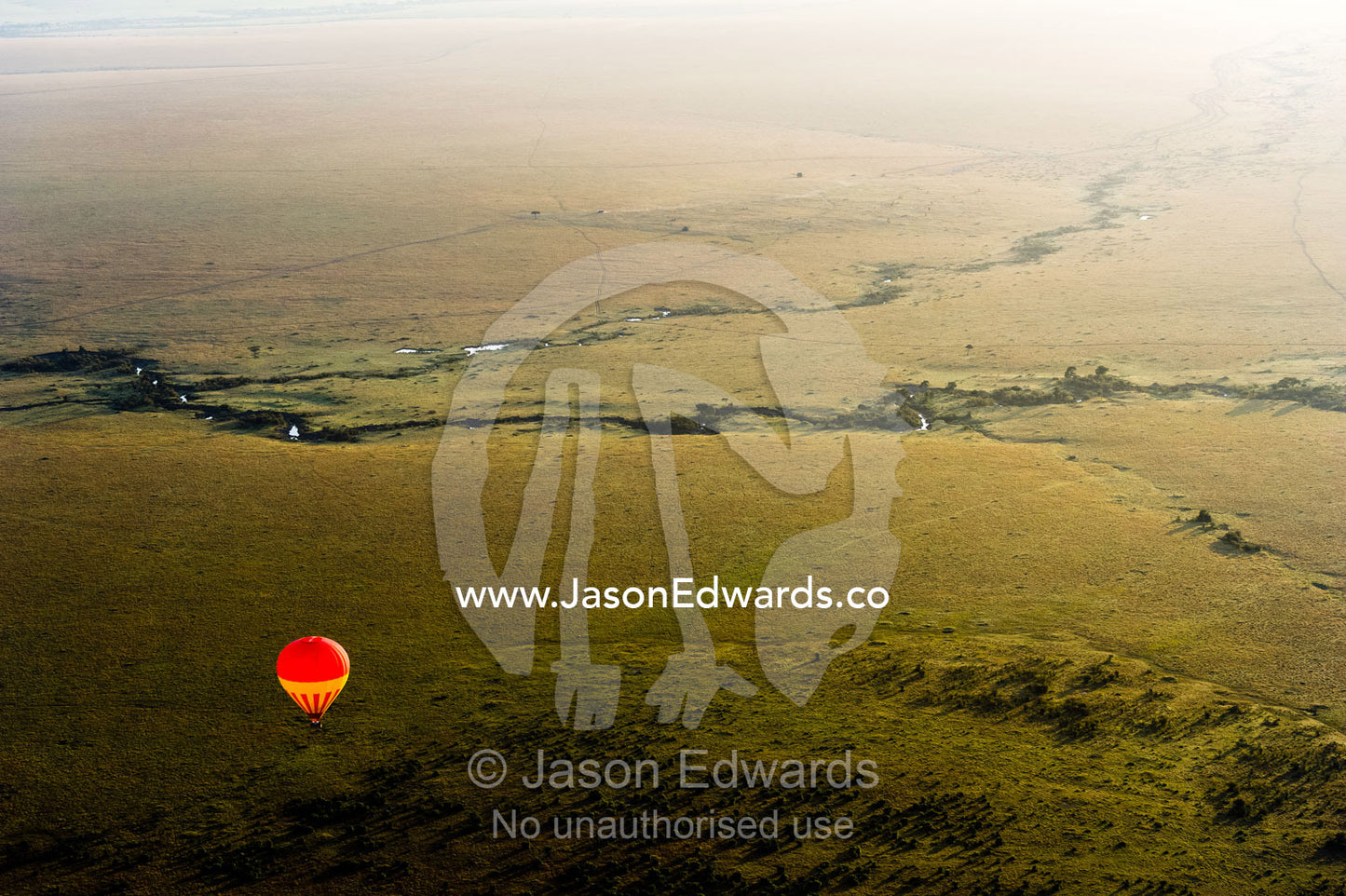 A hot air balloon floating over the vast short grass plains of the African savannah. Maasai Mara National Reserve, Masai Mara, Narok County, Kenya.