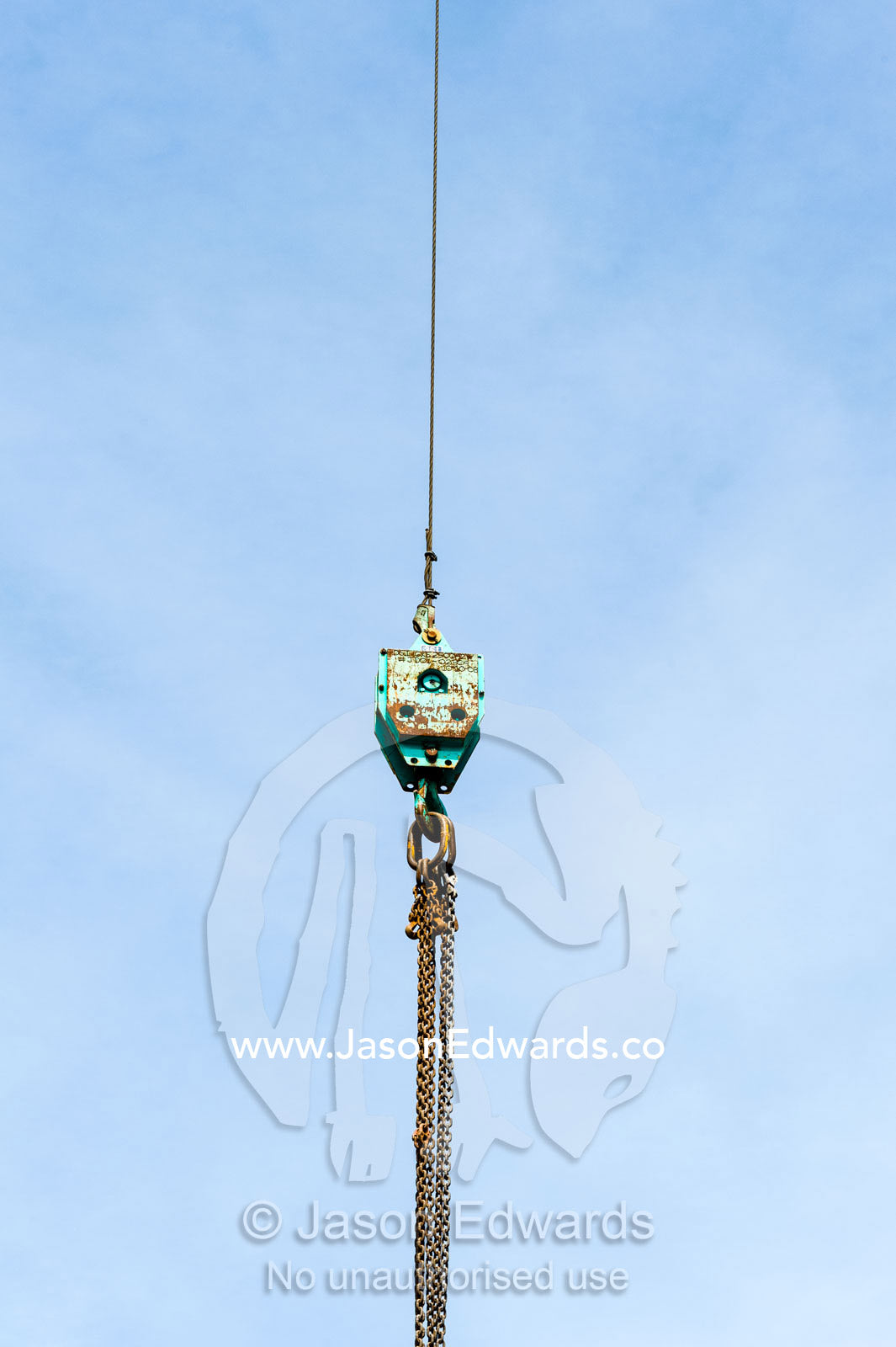 Steel chains hanging from a crane hook on a construction site. Christchurch, South Island, New Zealand.