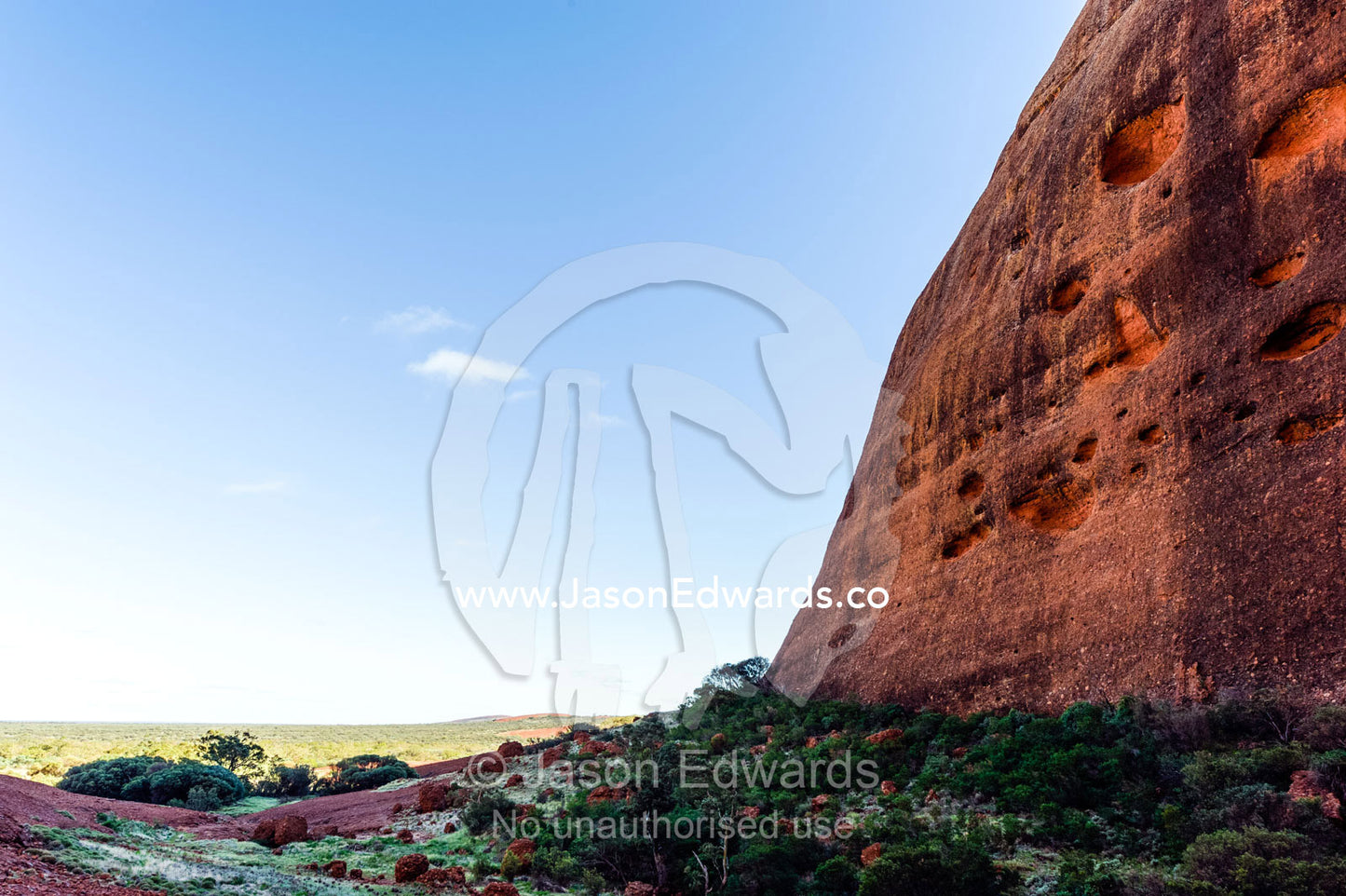 A sheer wall of sandstone casts a shadow over a gorge in the Australian desert. Uluru Kata Tjuta National Park, Northern Territory, Australia.