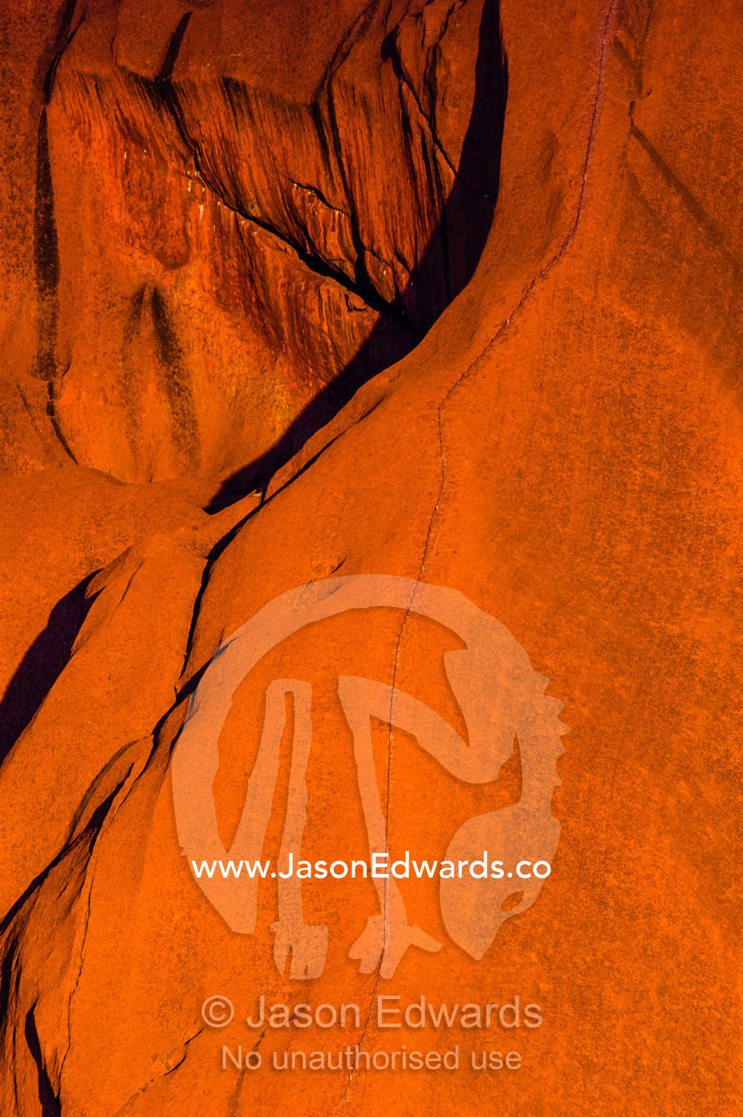 Sunset light on the folds and fissures of the blood red sandstone of Uluru. Uluru Kata Tjuta National Park, Northern Territory, Australia.