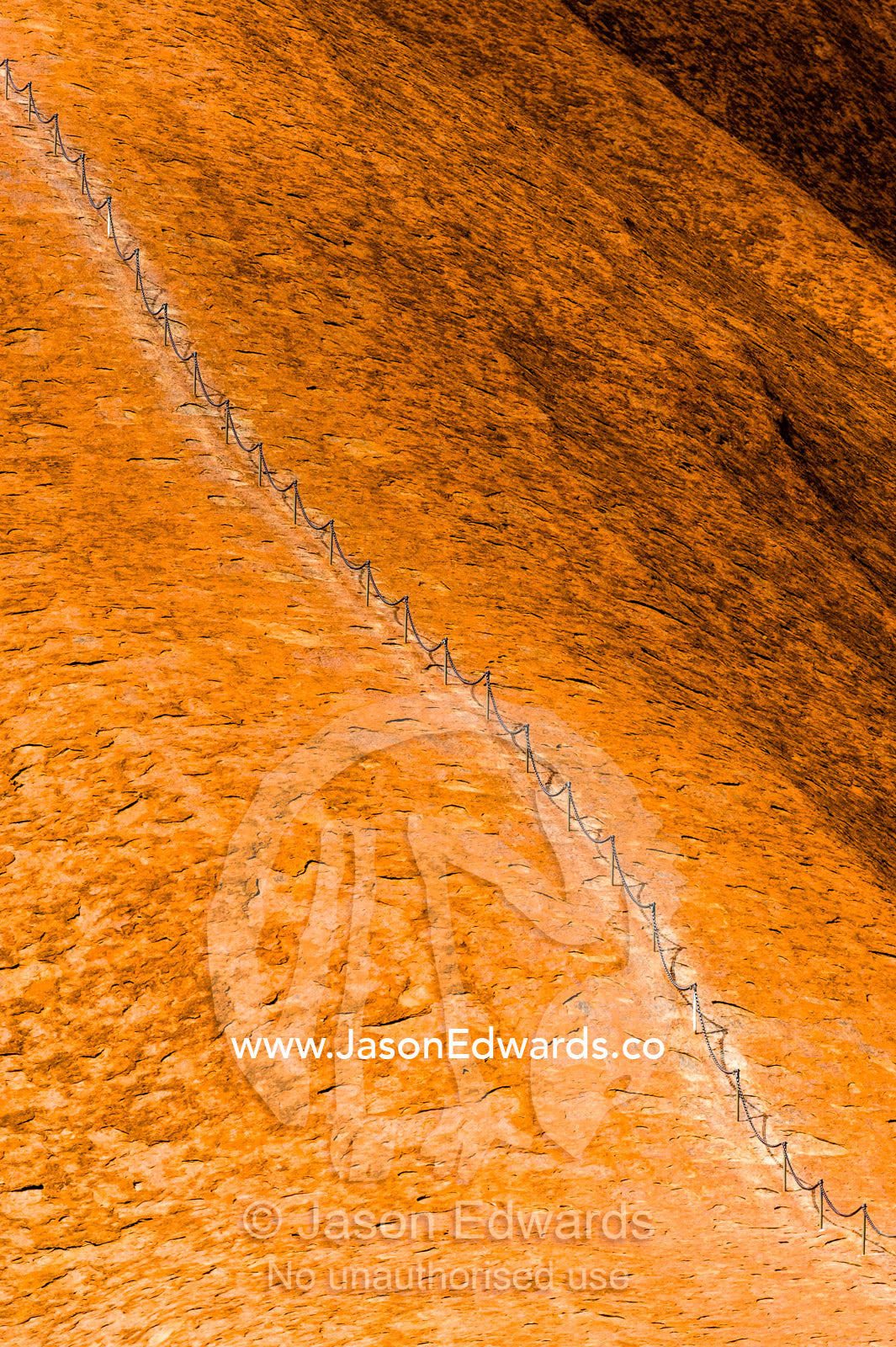 A chain assists tourists and walkers to climb the steep, smooth slope of Uluru. Uluru Kata Tjuta National Park, Northern Territory, Australia.