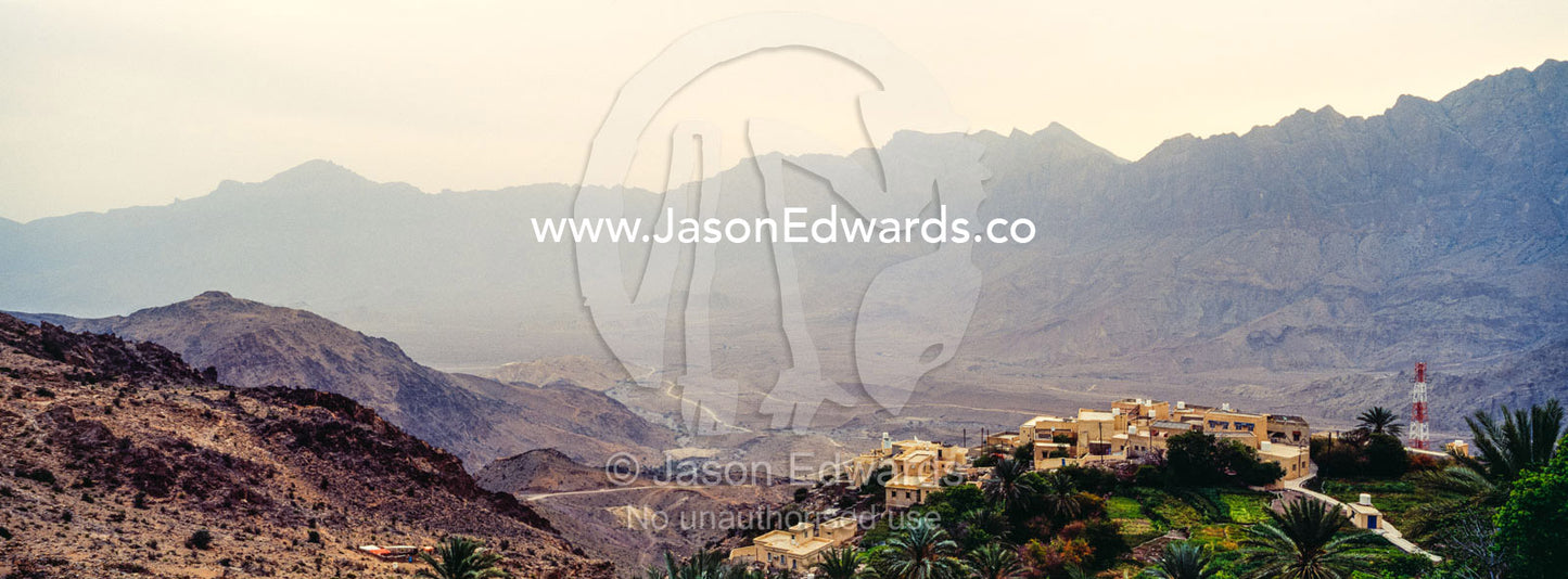 A village perched on a mountaintop overlooking an arid desert valley. Wakan Village, Wadi Mastal, Wilayt Nakhal, Al Batinah South Governorate, Sultanate of Oman.