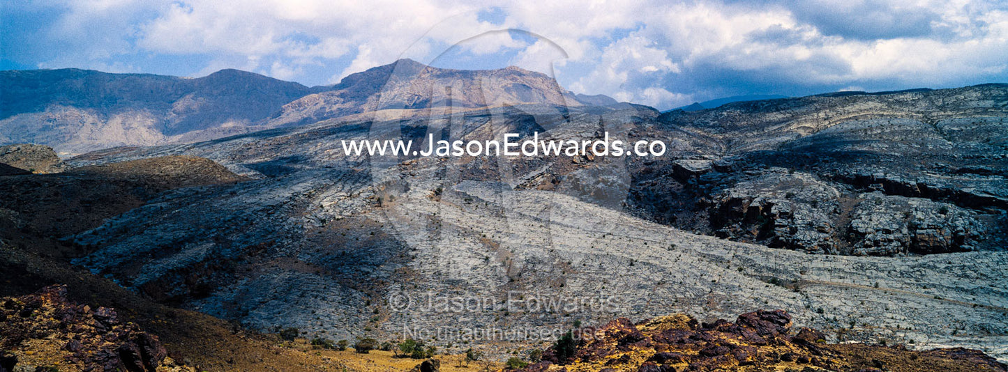 The arid rocky slopes of a prehistoric and volcanic desert landscape. Jebel Shams, Al Hajar Mountains, Sultanate of Oman.