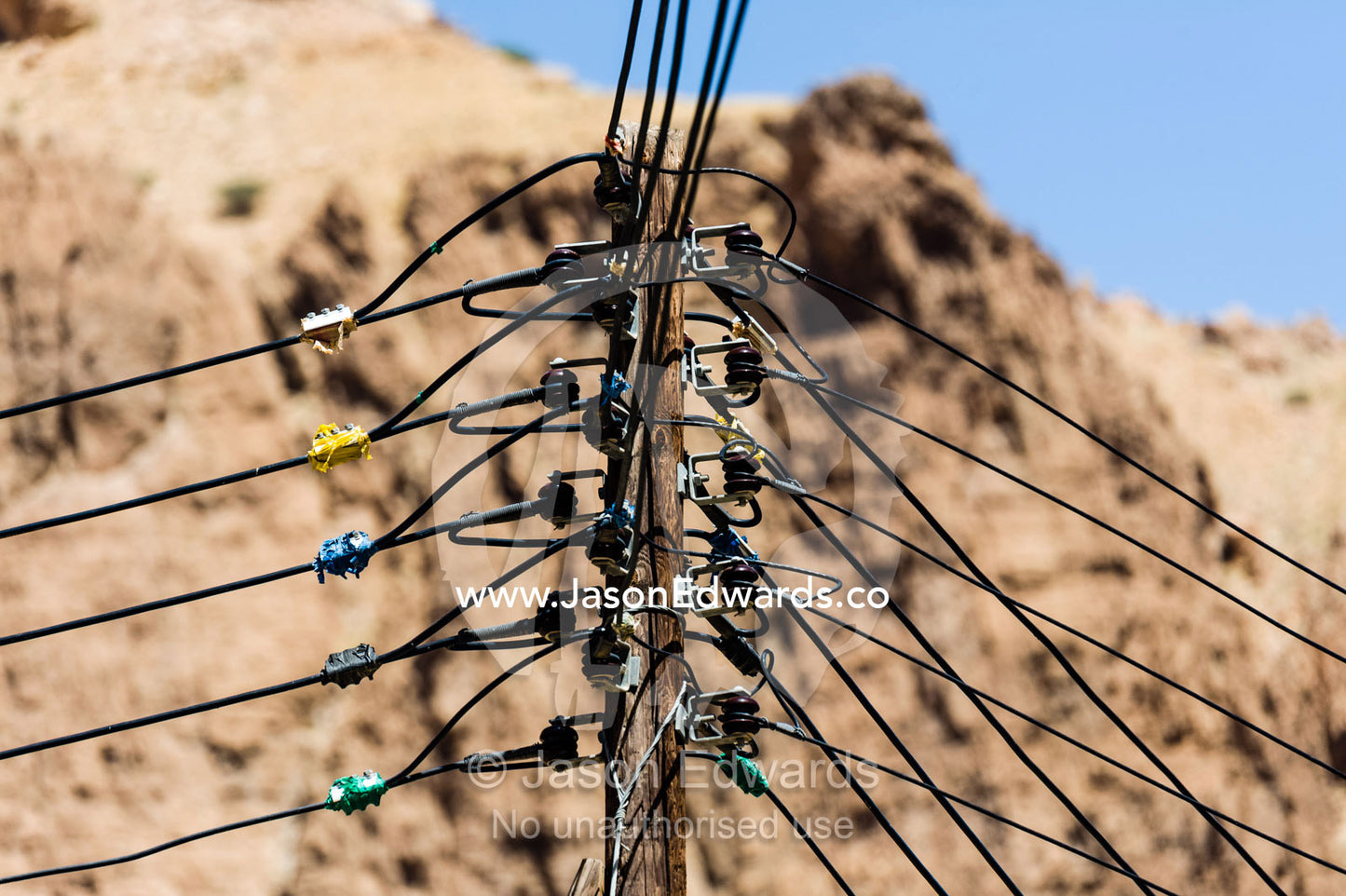 An electricity pole in a mountain village holds many connected wires. Mibam, Wadi Tiwi, Sur Al Sharqiyah South Governorate, Sultanate of Oman.