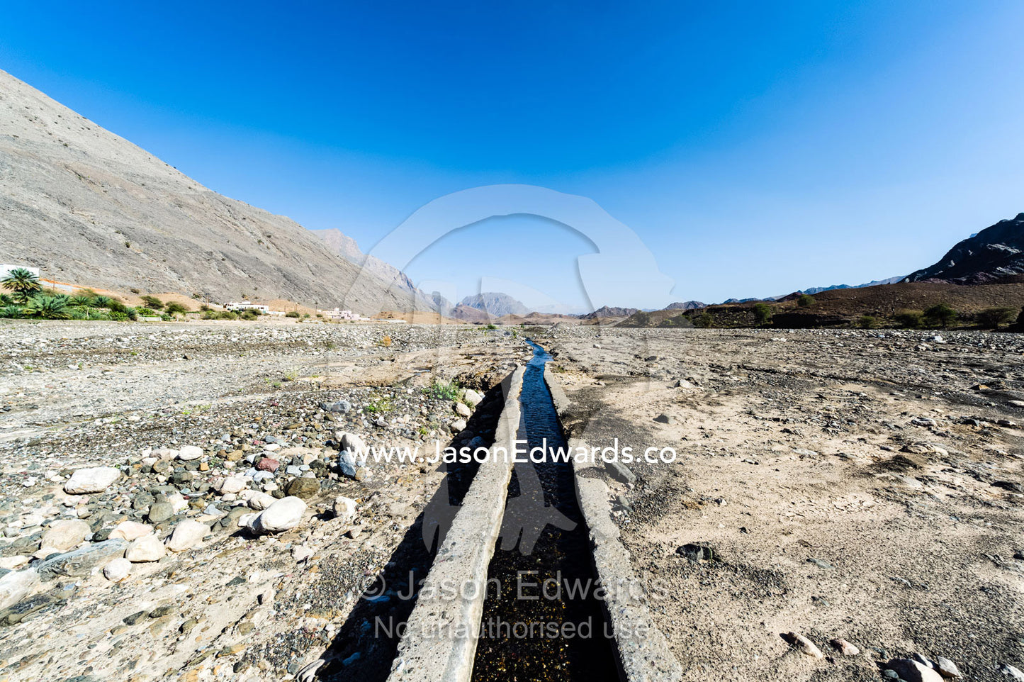 Water runs through a falaj in the desert and is used to irrigate crops and livestock in remote villages. Wadi Fanja, Dima Wal Taeen, North Al Sharqiyah Governorate, Sultanate of Oman.