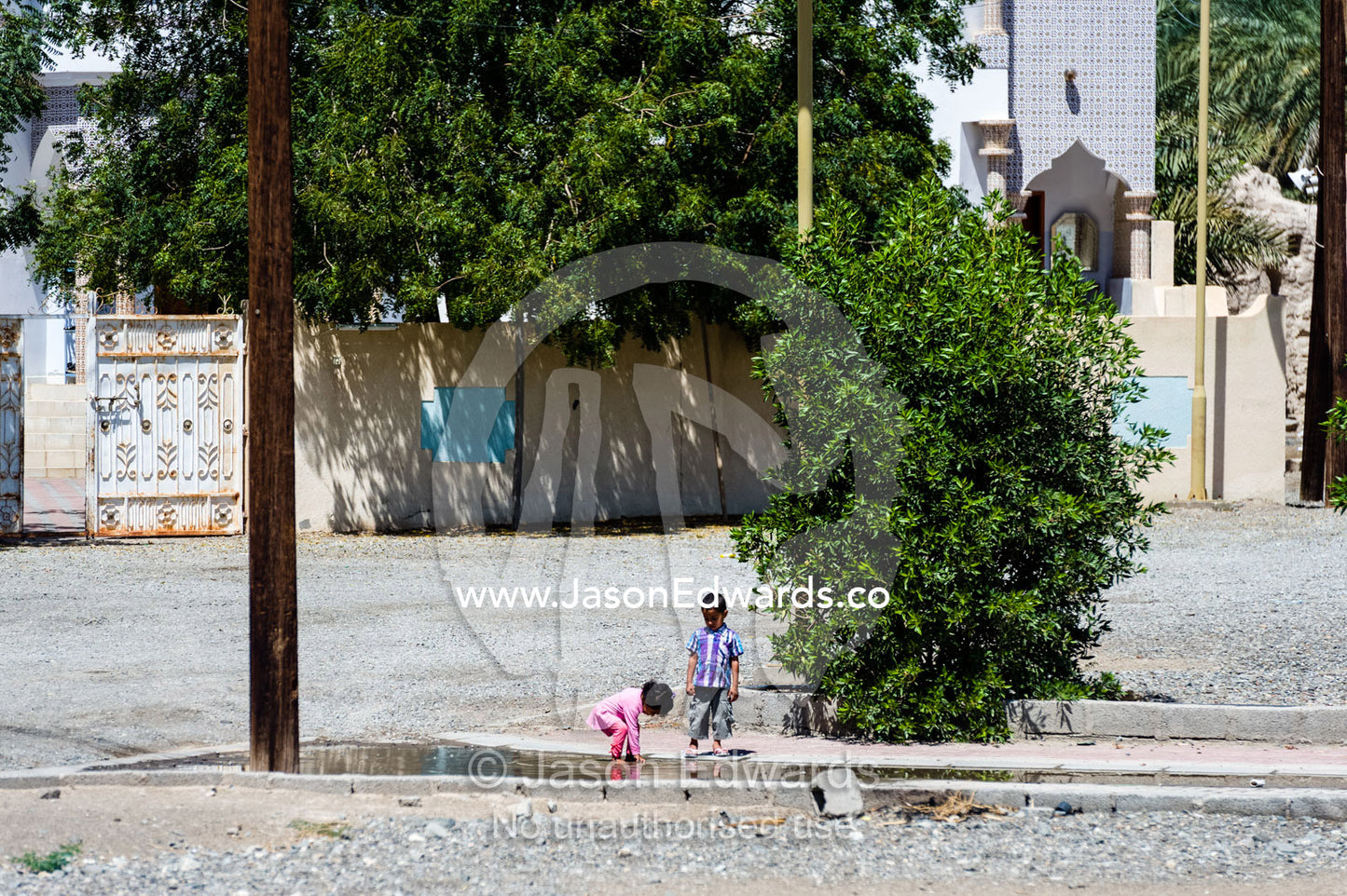 Children play in a pool of water in a desert village. Ibra, Ash Sharqiyah Region, Sultanate of Oman.