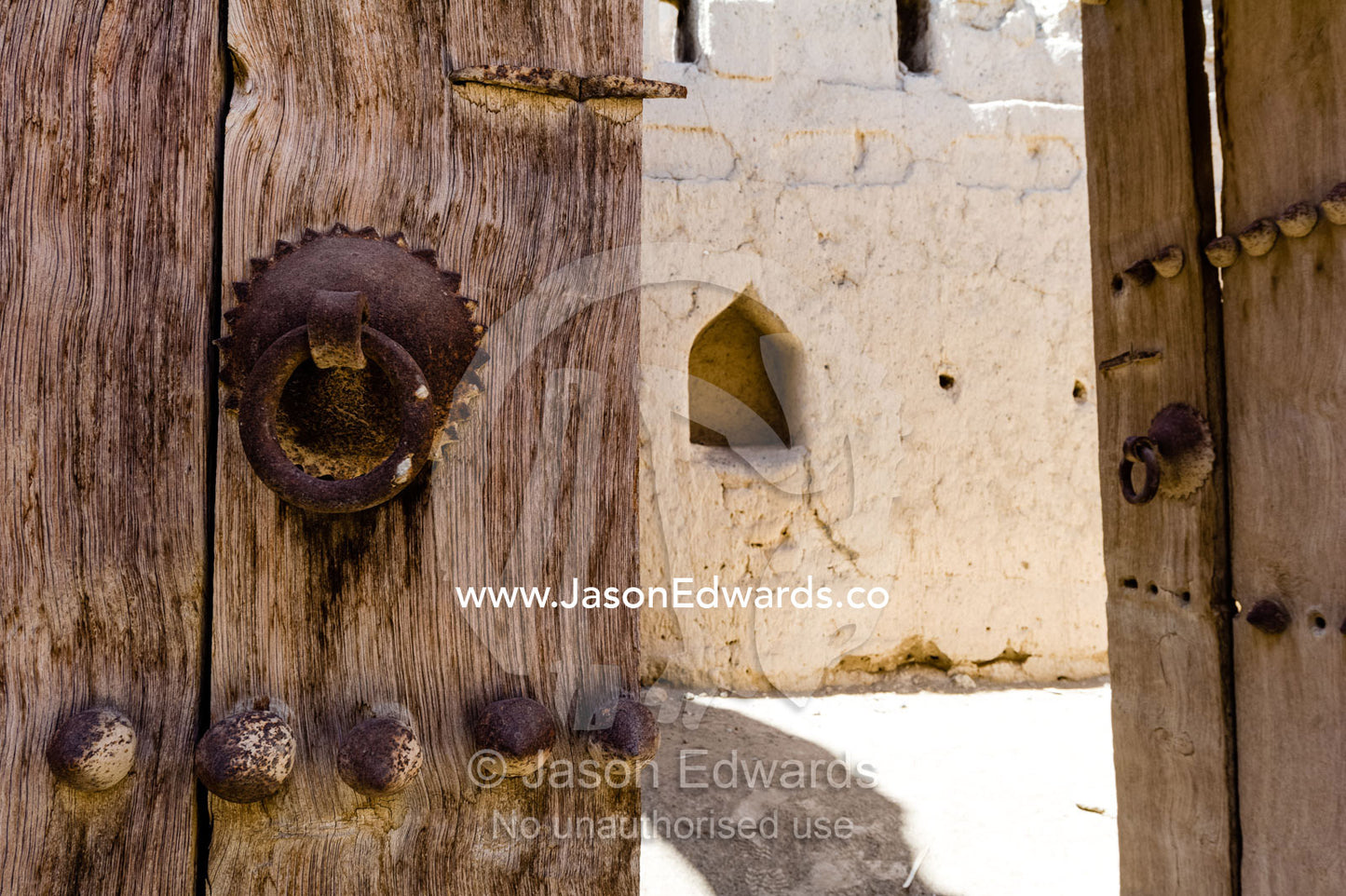 A rusting steel knocker on a timber door in an ancient desert village. Ibra, Ash Sharqiyah Region, Sultanate of Oman.