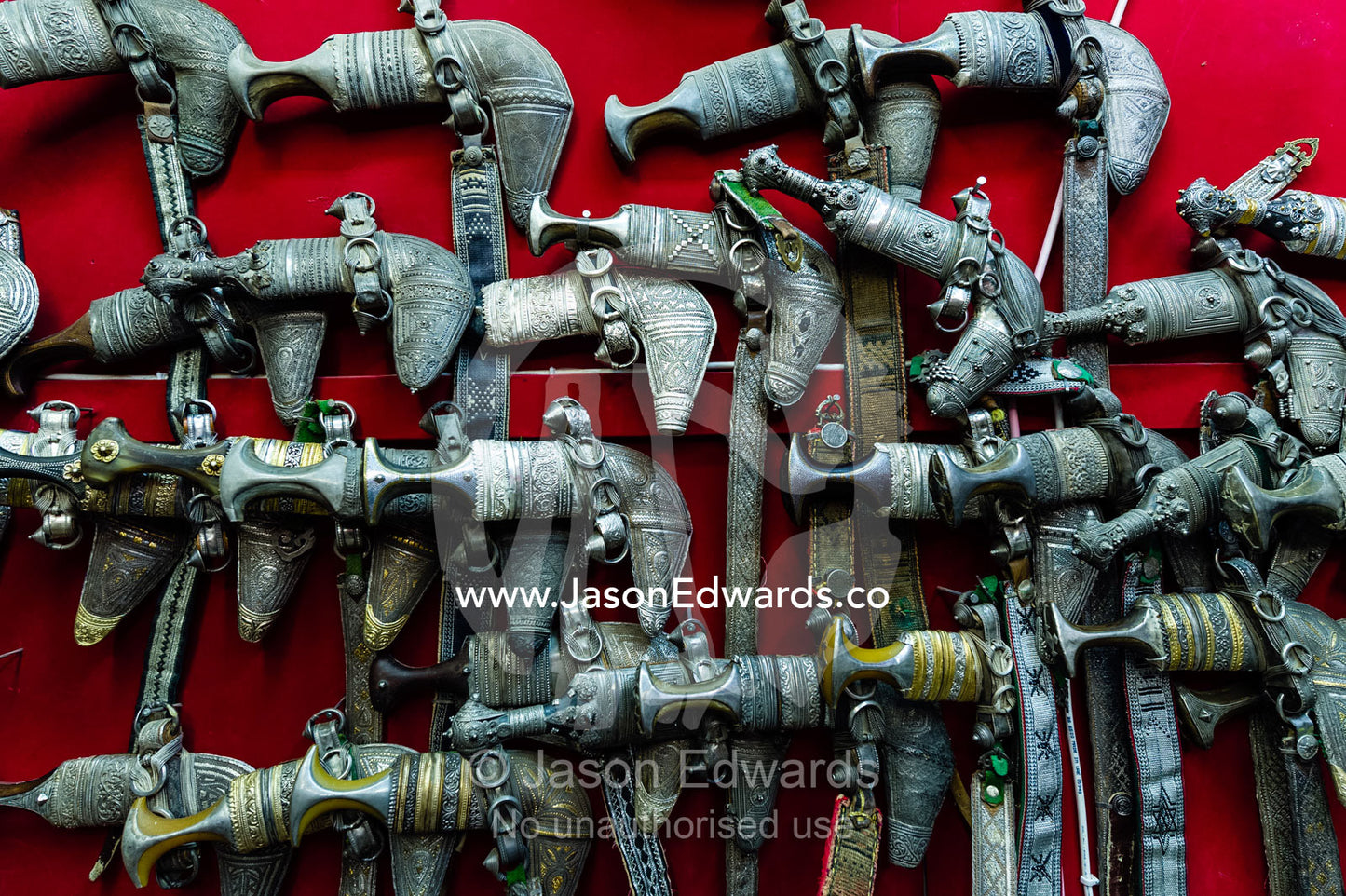 A wall displaying silver khanjar knives for sale in a souq. Mutrah Souq, Muscat, Sultanate of Oman.