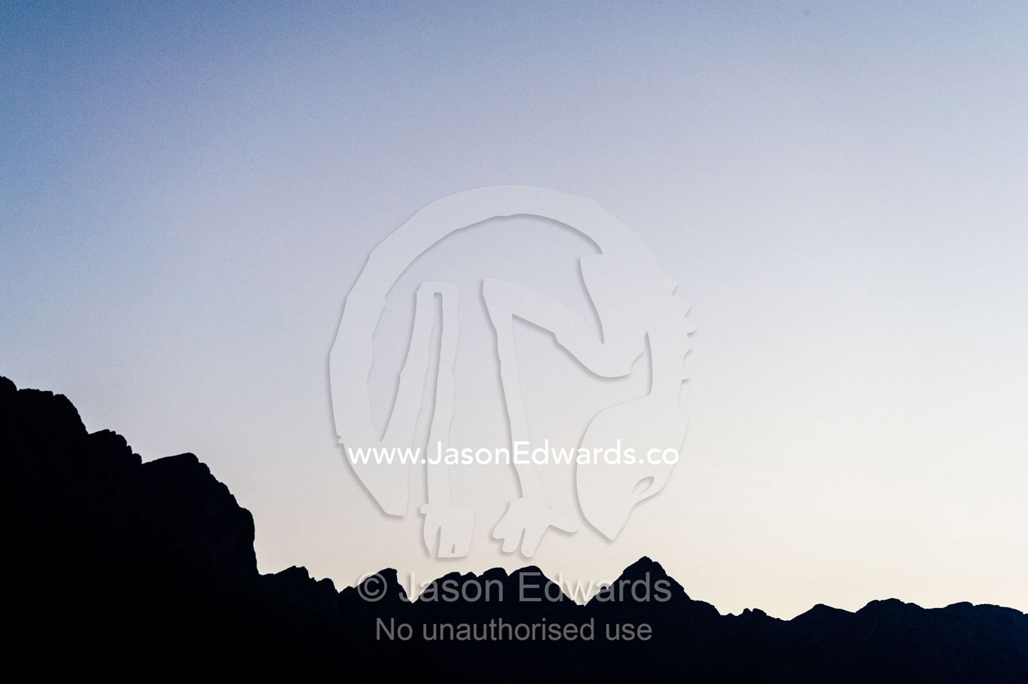 The jagged silhouette of a desert mountain ridge after sunset. Wadi Nakhar, Al Hamra, Ad Dakhiliyah Region, Sultanate of Oman.