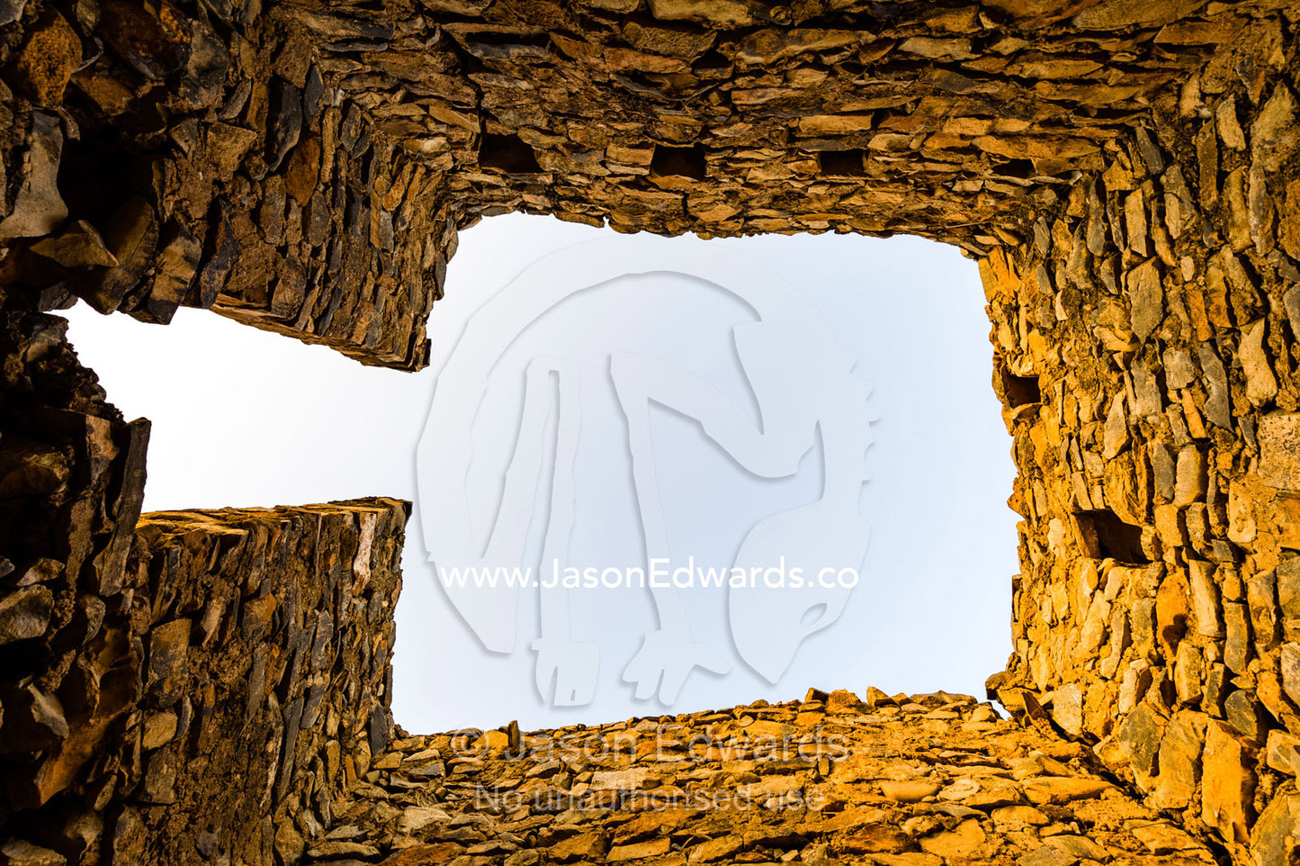 The sky is visible through the the missing roof of an ancient handmade stone home in an abandoned village. Wadi Nakhar, Al Hamra, Ad Dakhiliyah Region, Sultanate of Oman.