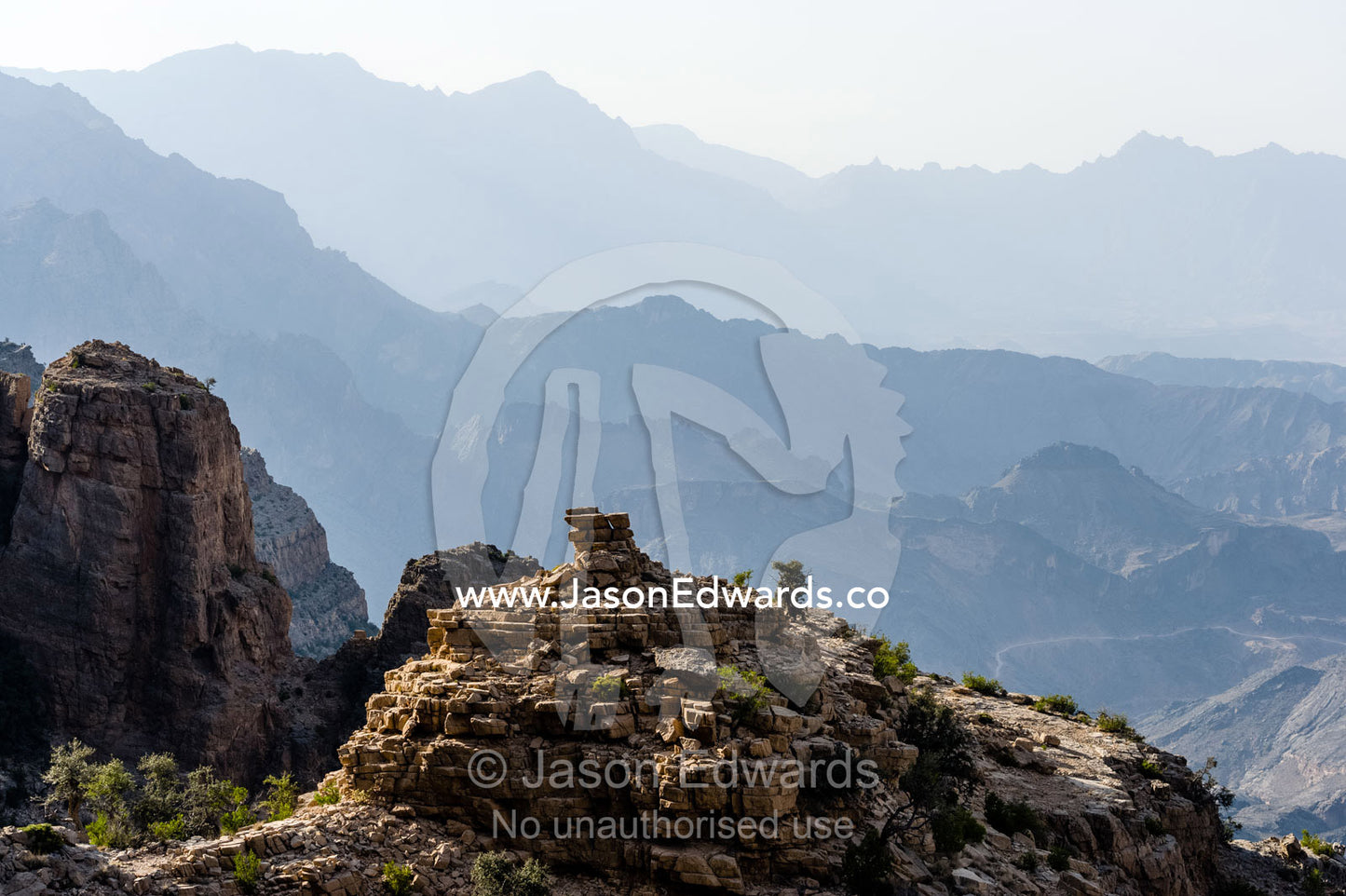 Arid jagged mountains overlook an eroded and inhospitable rocky desert valley. Hatt, Wadi Bani Awf, Snake Gorge, Western Hajar Mountains, Ad Dakhiliyah Region, Sultanate of Oman.