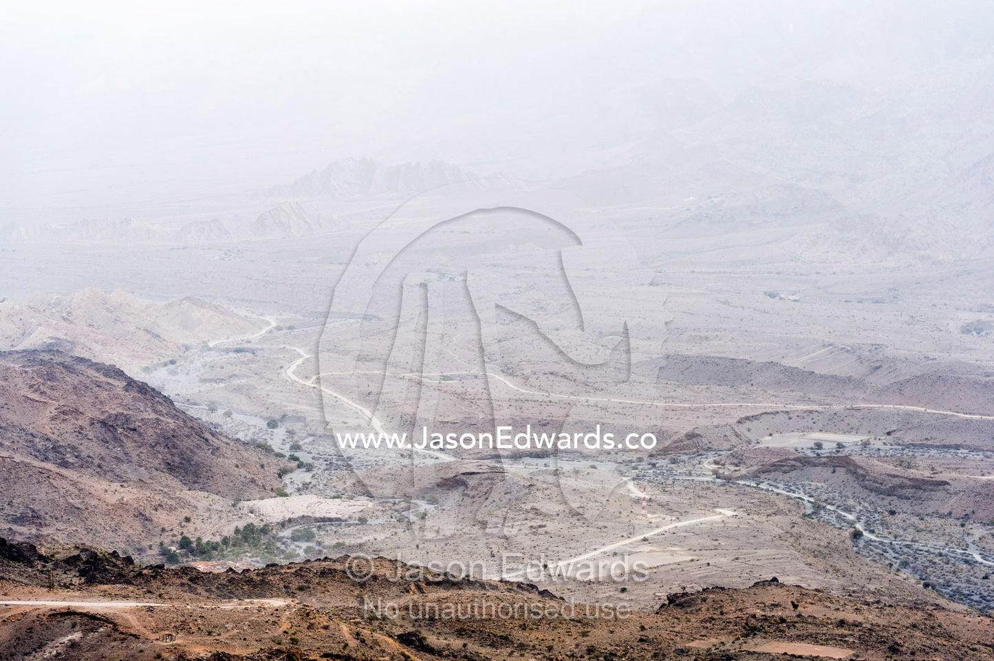 A dirt trail winds it's way through an arid desert valley. Wakan Village, Wadi Mastal, Wilayt Nakhal, Al Batinah South Governorate, Sultanate of Oman.