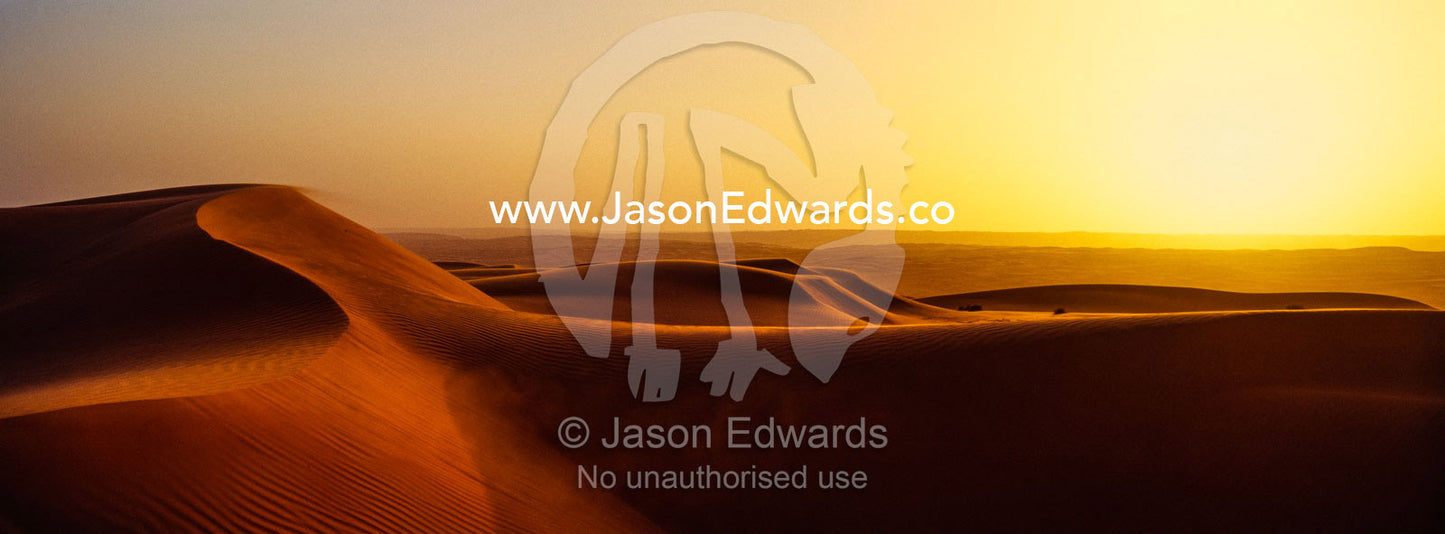 Sunset shines on sand dunes in the desert. Wahiba Sands, Ramlat al-Wahiba, Sharqiya Sands, Sultanate of Oman.