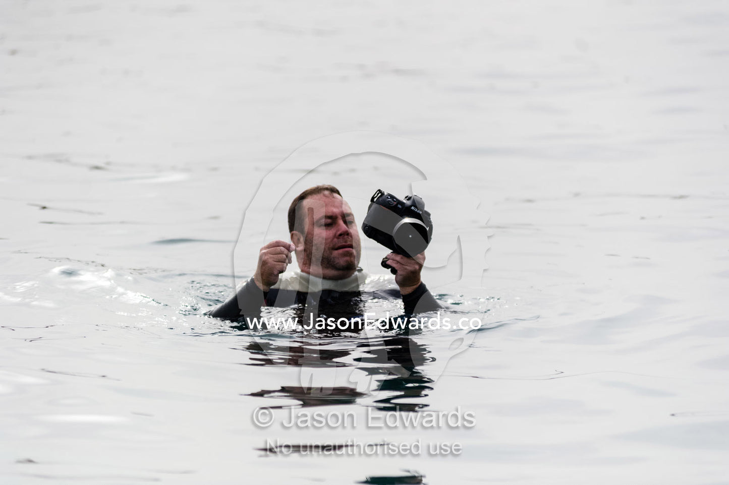 A photographer carefully using his camera in the ocean without an underwater housing. Daymaniyat Islands Nature Reserve, Wilayat AlSeeb, Barka, Sultanate of Oman.