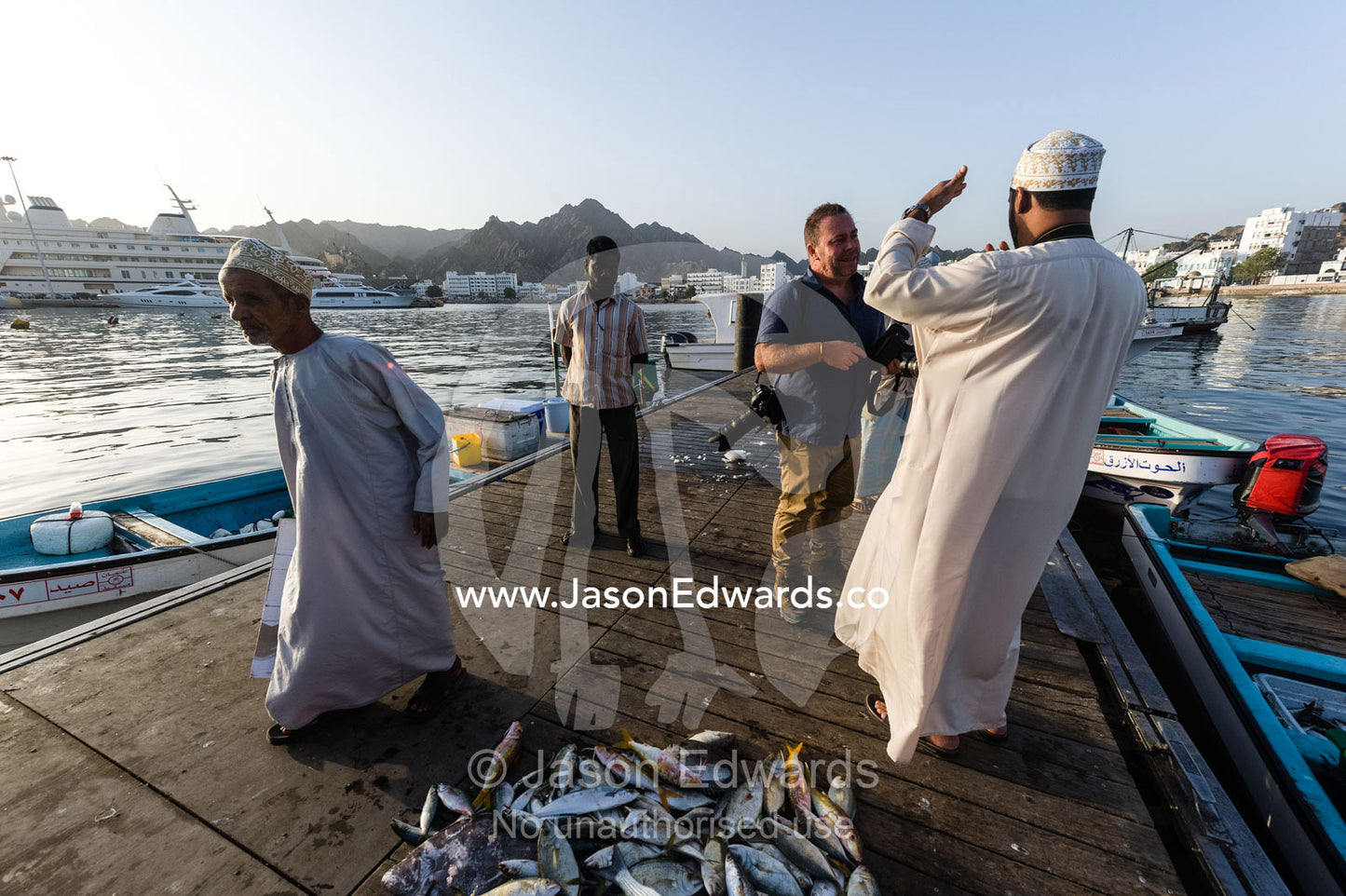 A photographer discussing locations with his fixer at a fish market. Mutrah Fish Market, Muscat, Gulf of Oman, Sultanate of Oman.