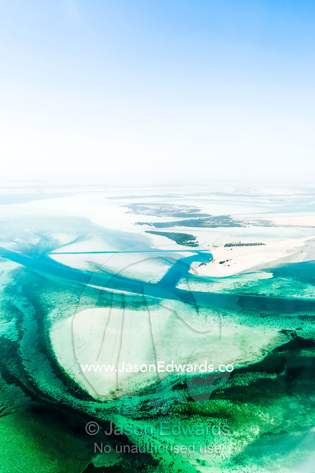 Turquoise tidal flats and coastal sea channels surrounded by arid desert sands. Emirate of Abu Dhabi, Abu Dhabi, Persian Gulf, United Arab Emirates.