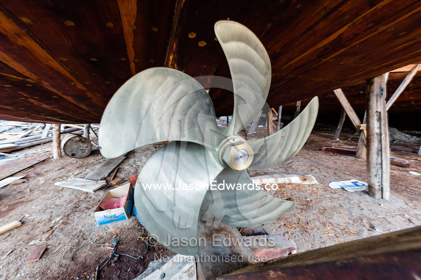 The handmade construction of an ancient timber dhow in a shipyard and a stainless steel propeller. Sur, Ash Sharqiyah Region, Gulf of Oman, Sultanate of Oman.