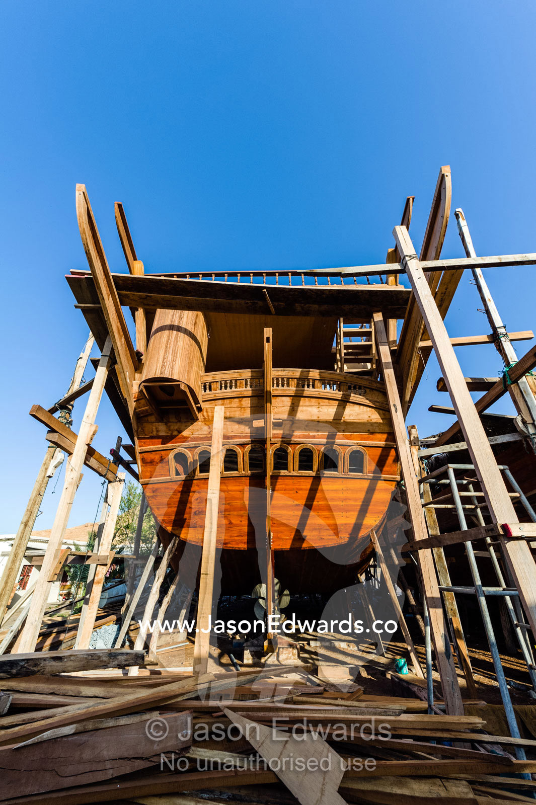 Scaffolding supports the hull during handmade construction of an ancient timber dhow. Sur, Ash Sharqiyah Region, Gulf of Oman, Sultanate of Oman.